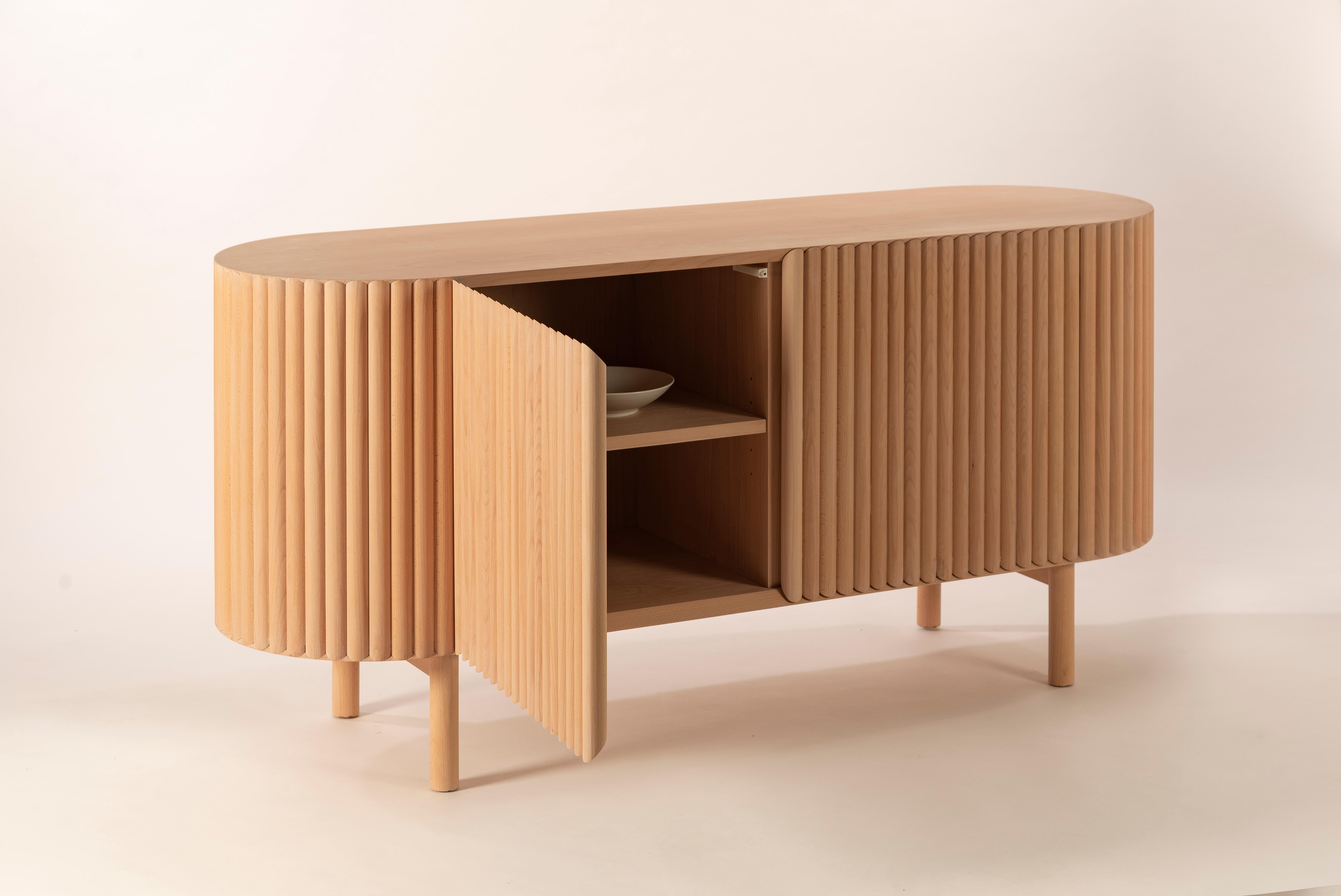 Between the sculpture and the functionality of the object, the RIMA credenza is inspired by the dynamism and the cadence of a poem, drawing all the attention to the wooden slats that are repeated one after the other to form a texture that embraces