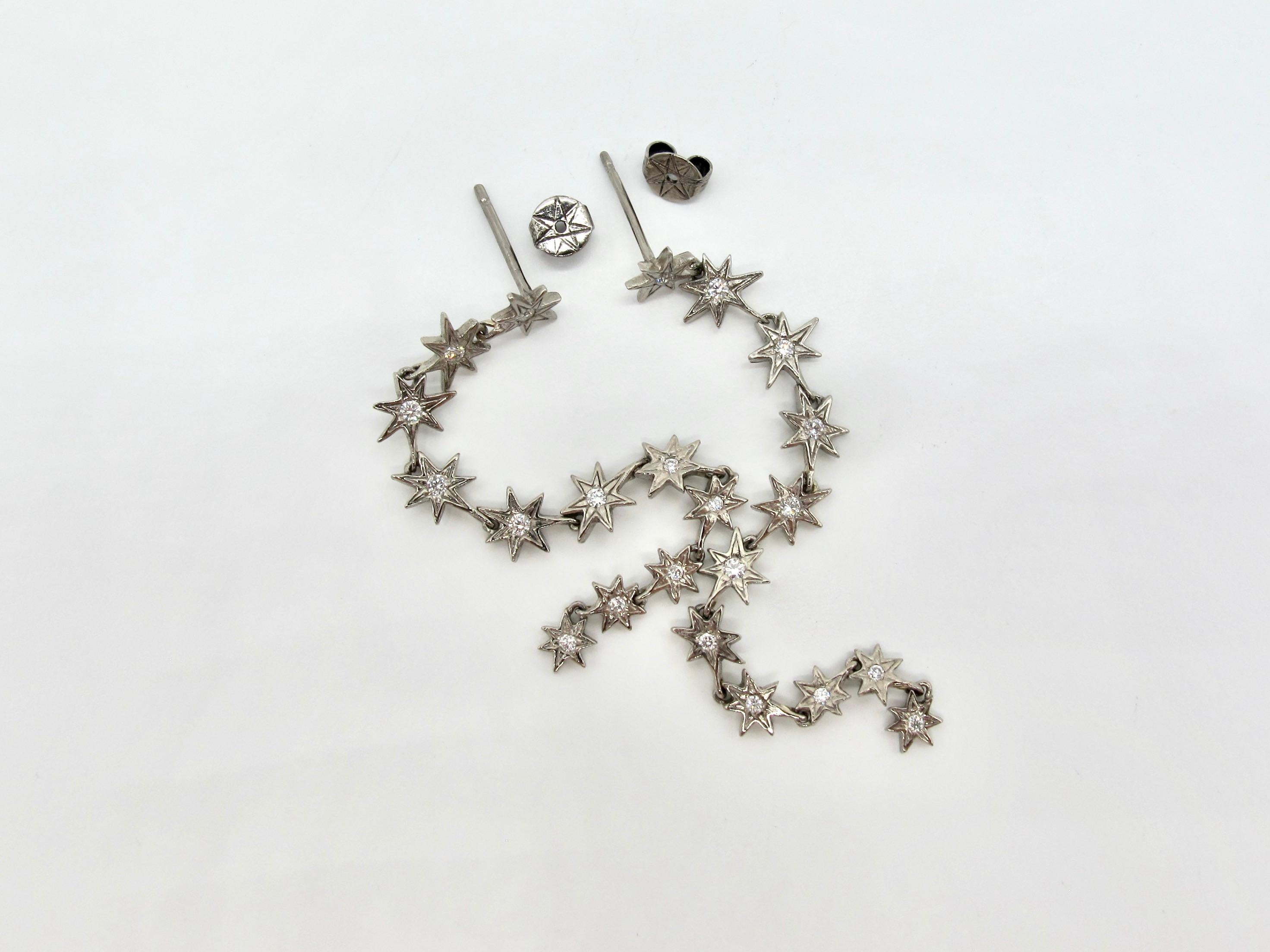 Questo set di orecchini in oro 18 carati è caratterizzato da ventidue stelle a sette punte firmate RIMA e incastonate con diamanti bianchi a taglio brillante (di dimensioni variabili tra 1,65 e 1,3 mm di diametro). Gli orecchini a goccia con stella