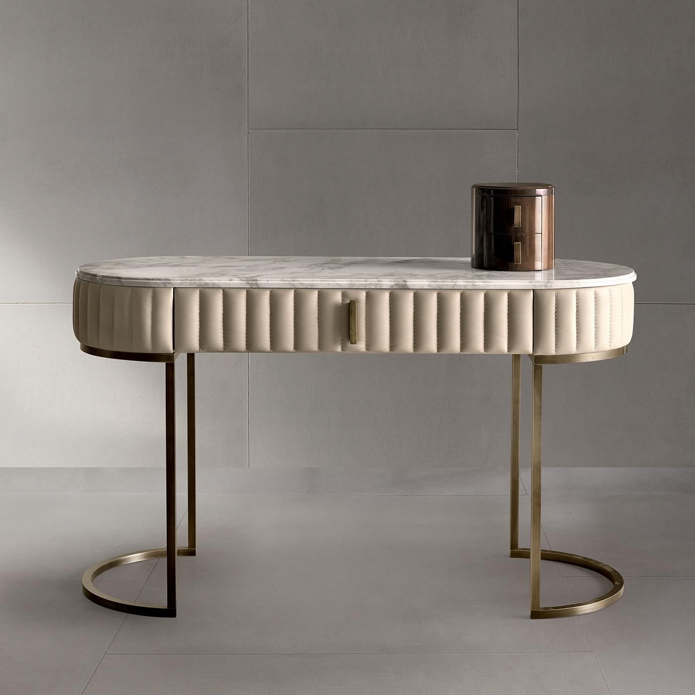 The contemporary style of this original vanity table provides a stylish surface for perfume, makeup, and jewelry. Two burnished brass tubular legs support an elongated oval Emperador marble top with a large rim upholstered in grosgrain design gray