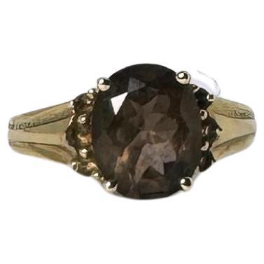 Make a sophisticated statement with this stunning vintage 14K yellow gold smoky quartz ring. The centerpiece is a captivating oval-cut smoky quartz, estimated at 2 carats, designed to be an absolute eye-catcher. Adding to its charm, six smaller