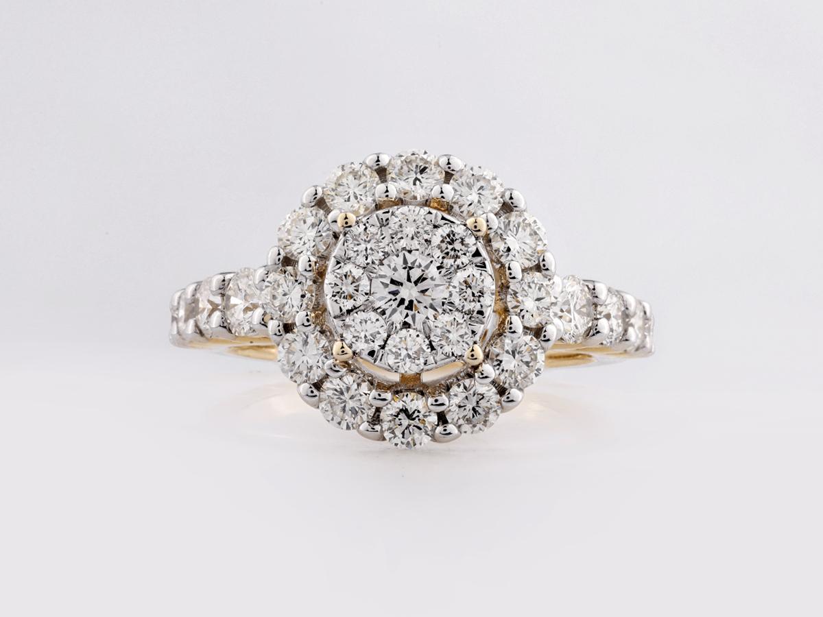 Il s'agit d'une bague en diamant dont le centre est constitué d'une grappe de diamants ronds, entourée d'un halo étincelant de diamants plus petits. La bande est rehaussée de diamants supplémentaires, ce qui lui confère un éclat supplémentaire. La