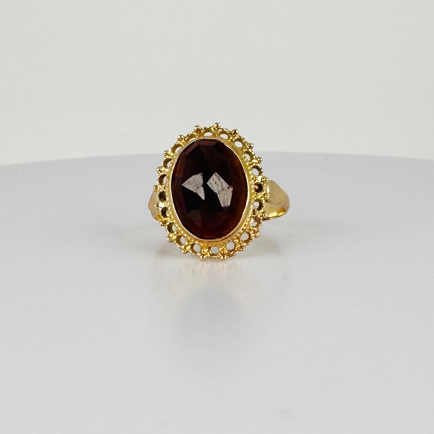 Stunning! Take a look at this beautiful vintage ring with an oval garnet and set in detailed gold. The soft sparkle of the faceted stone catches the light and accentuates your look. Combine it with other jewels for a layered look, or let this