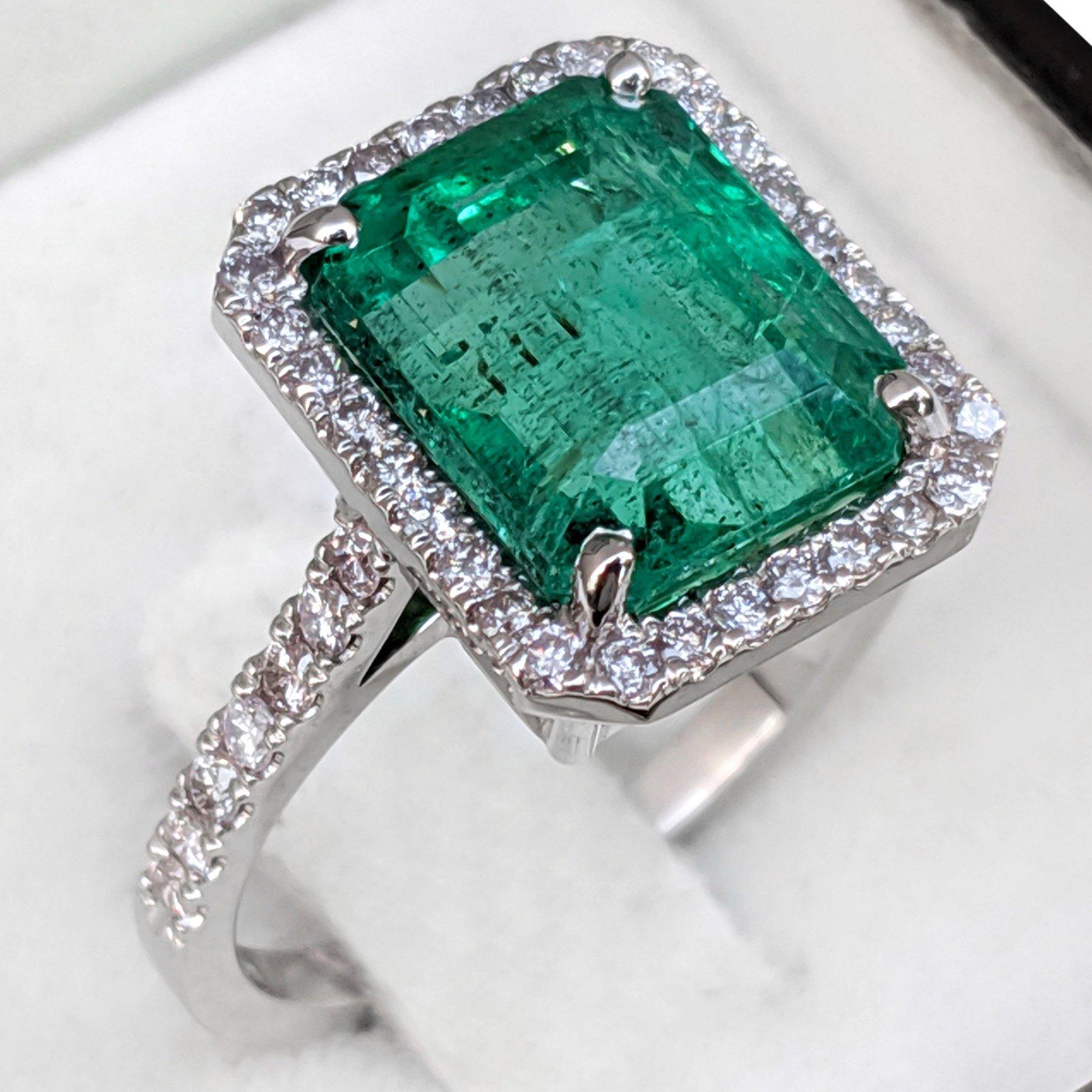 Cette bague exquise est ornée d'une captivante émeraude verte de 6,48 carats en guise de pierre centrale, rayonnant de couleurs vibrantes et d'élégance. L'émeraude est flanquée de pierres latérales en diamant rose fantaisie, totalisant 0,62 carat,