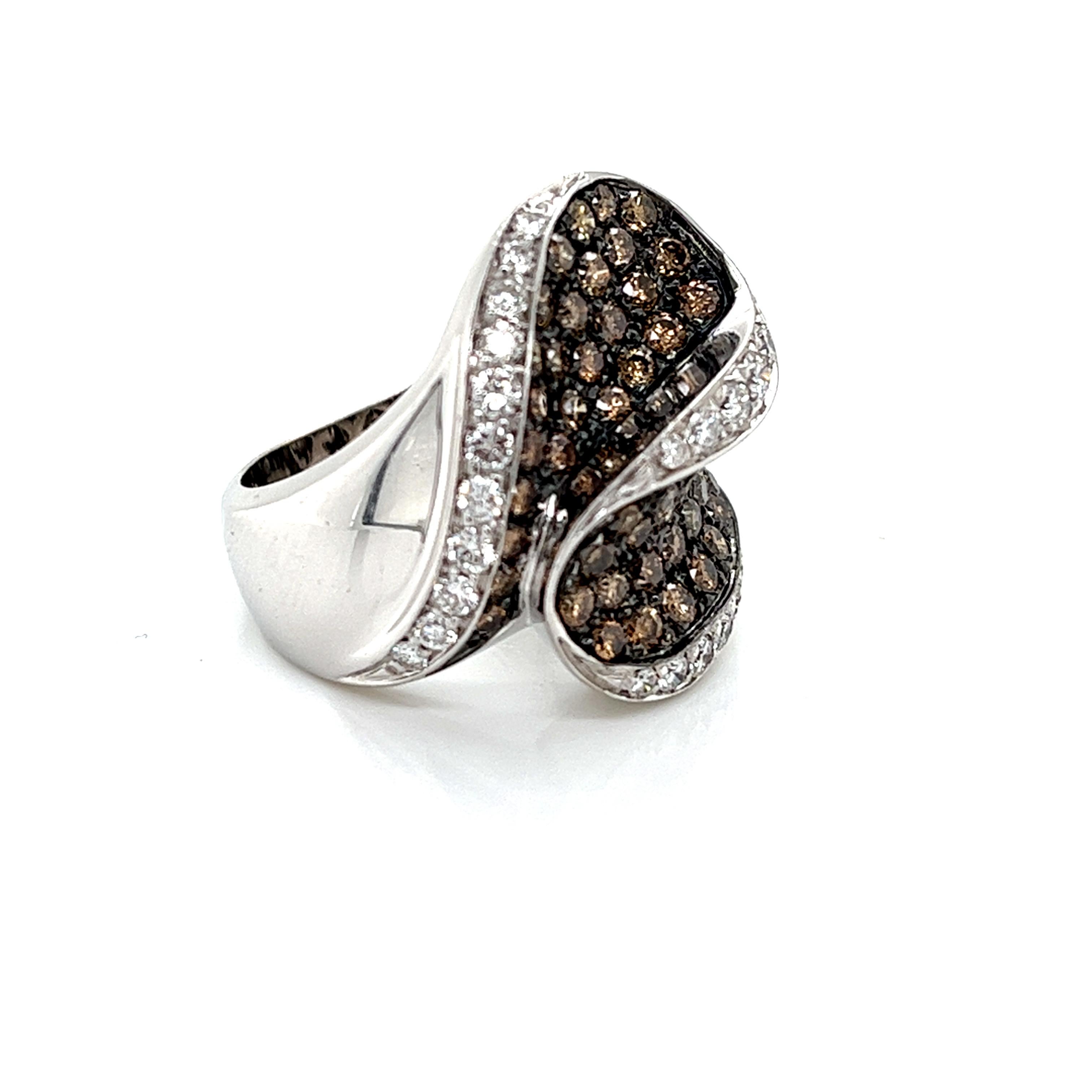 A captivating wave ring crafted in 18kt white gold, adorned with a graceful blend of champagne-colored diamonds and shimmering white diamonds. This design beautifully evokes the ebb and flow of the ocean, where the warm hues of champagne diamonds