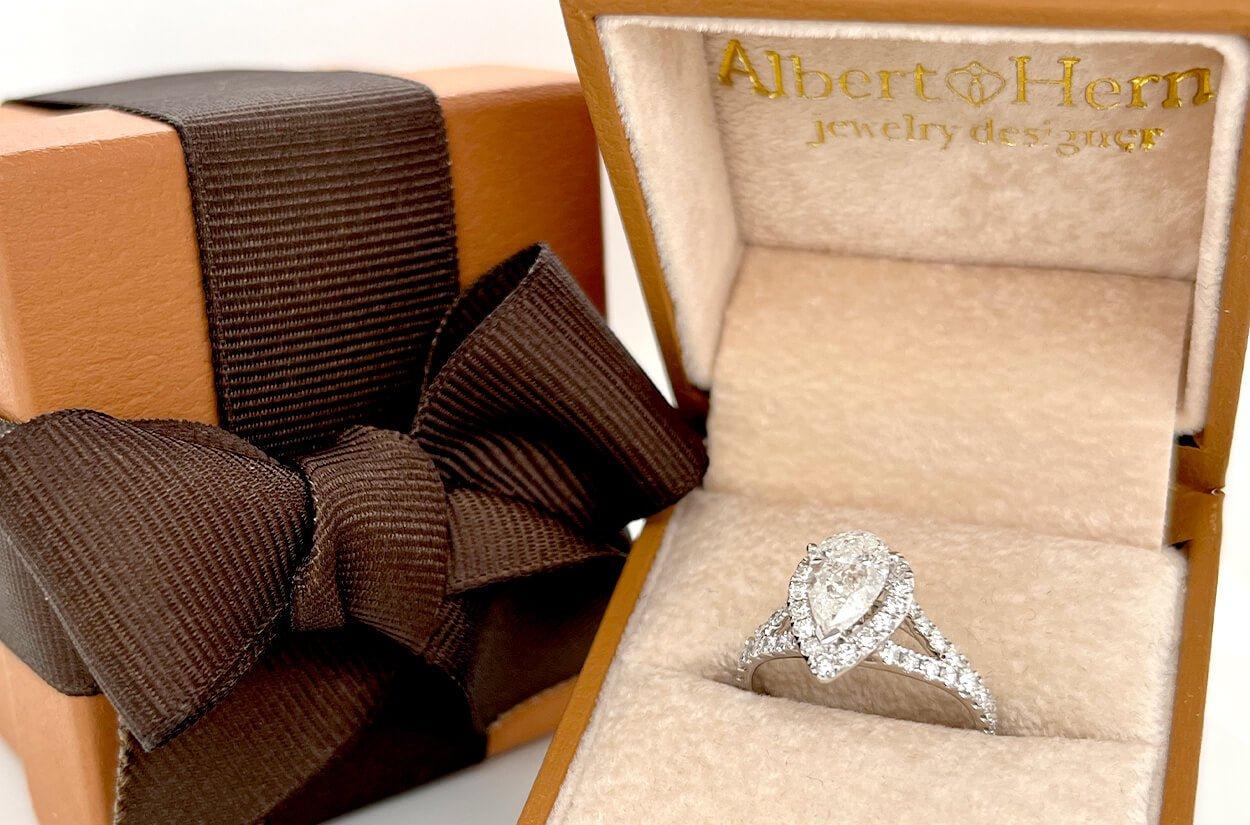 Simbolo splendido di amore e grazia senza tempo, questo squisito anello di fidanzamento a raggiera in oro bianco 18 carati ha come cuore uno splendido diamante a forma di pera, cullato da un delicato abbraccio di brillanti rotondi. La fusione