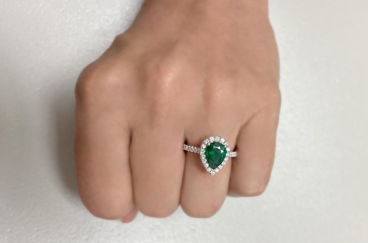 This Pear Shape Emerald ring is set in 18kt white gold and features a captivating halo setting of diamonds. The pear-shaped emerald at the center is elegantly surrounded by sparkling diamonds, enhancing its beauty and creating a luxurious contrast .