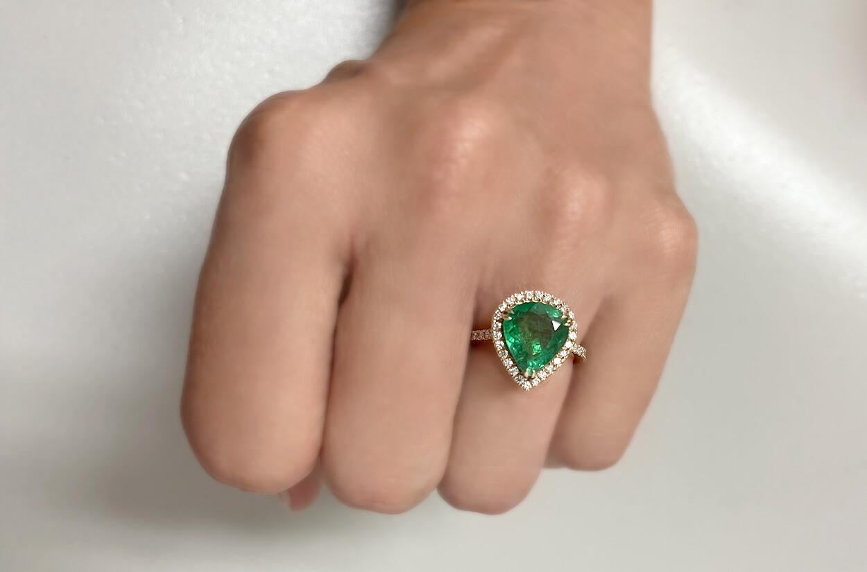 This Pear Shape Emerald ring is set in 18kt rose gold and features a captivating halo setting of diamonds. The pear-shaped emerald at the center is elegantly surrounded by sparkling diamonds, enhancing its beauty and creating a luxurious contrast