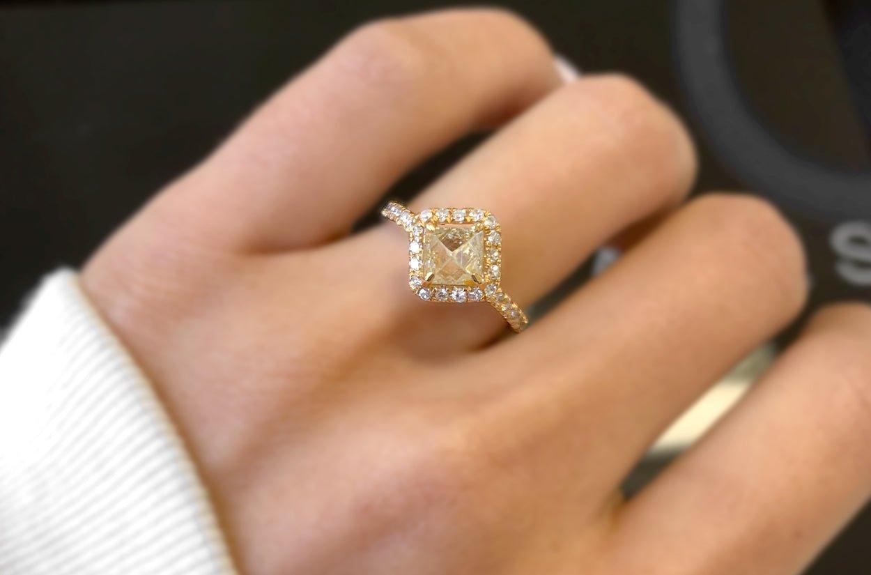 Une bague de fiançailles vraiment unique et enchanteresse, fabriquée en or 18kt, avec en son cœur un captivant diamant brut naturel, entouré d'un halo étincelant de diamants ronds brillants. Ce design unique en son genre symbolise la beauté des