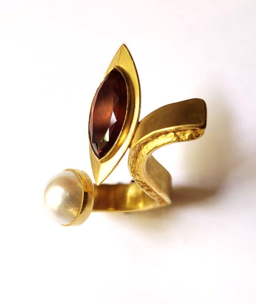 Magnificent ring made of 24 carat gold by Marc Wilpert. The unique design makes this ring a statement piece. The sparkling navette cut Madeira citrine next to the shiny mabée pearl with very good luster will complement any outfit.
Beautiful and