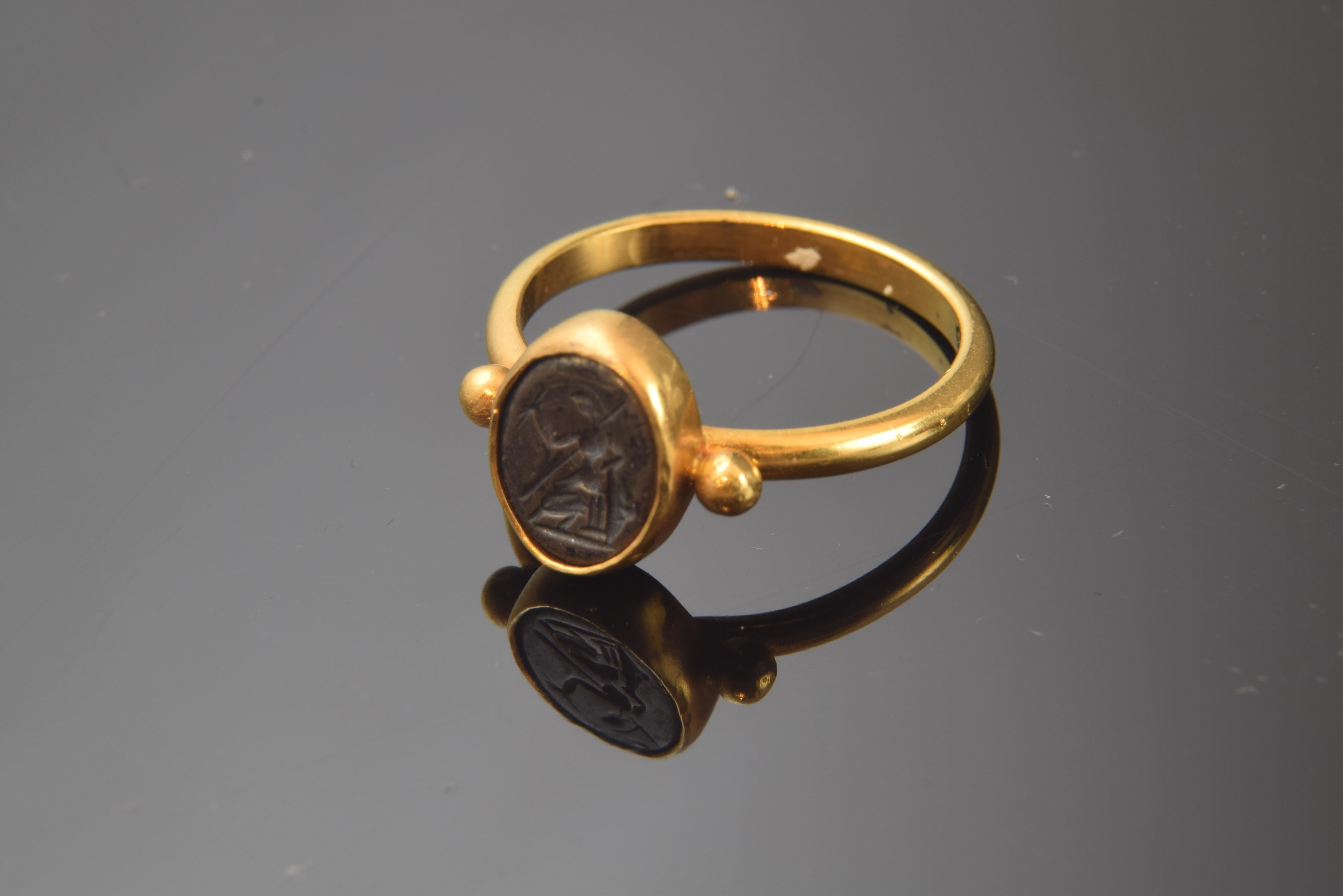 Ring with smooth gold band and two pearls flanking a central piece framed in another flat band of gold. This dark element, in bas-relief or 