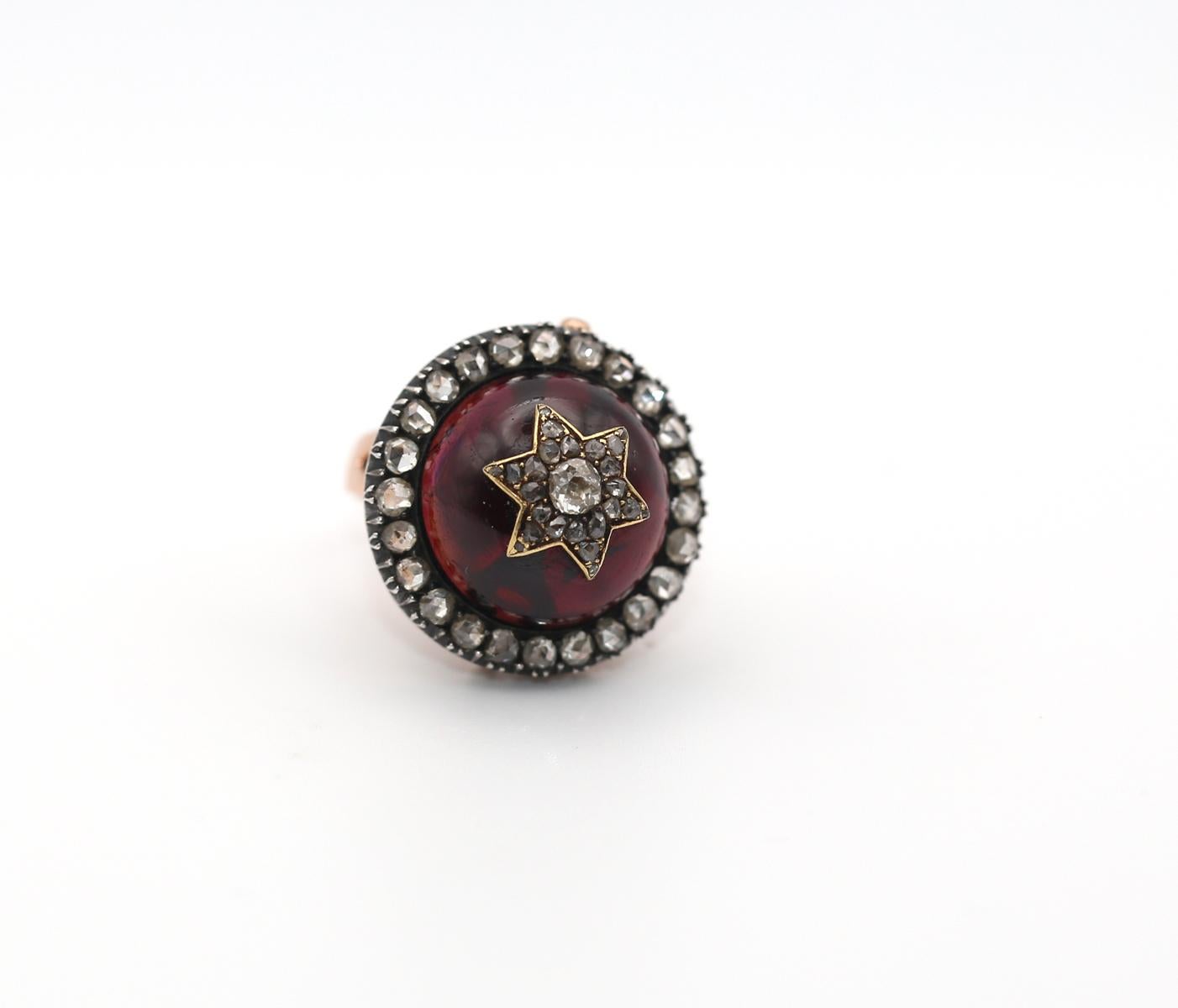 Fine and beautifully bold ring / brooch featuring a captivating round-shaped cabochon Garnet.  On top it is set with a Star of David with Old-mine Diamonds.

The main stone is surrounded by a halo of Old mine cut Diamonds, each displaying a