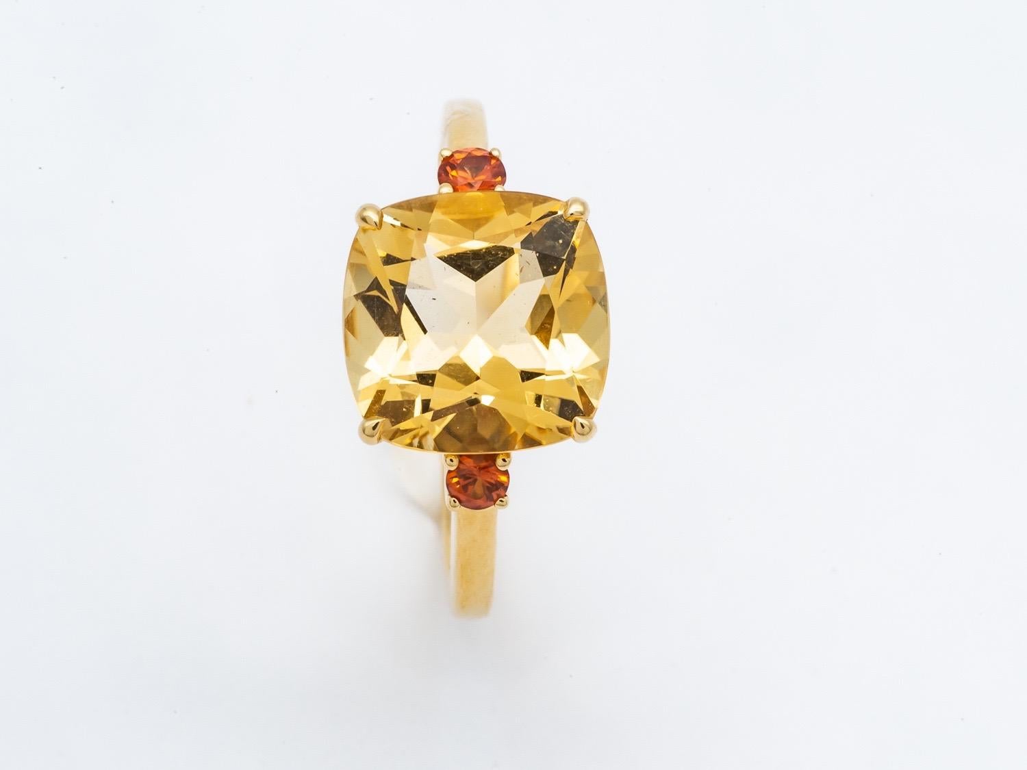 Discover this superb ring in 18-carat yellow gold, adorned with a magnificent cushion-shaped citrine and two orange sapphires. This ring is a true jewel of sophistication, combining the warm glow of yellow gold with the vibrancy of precious