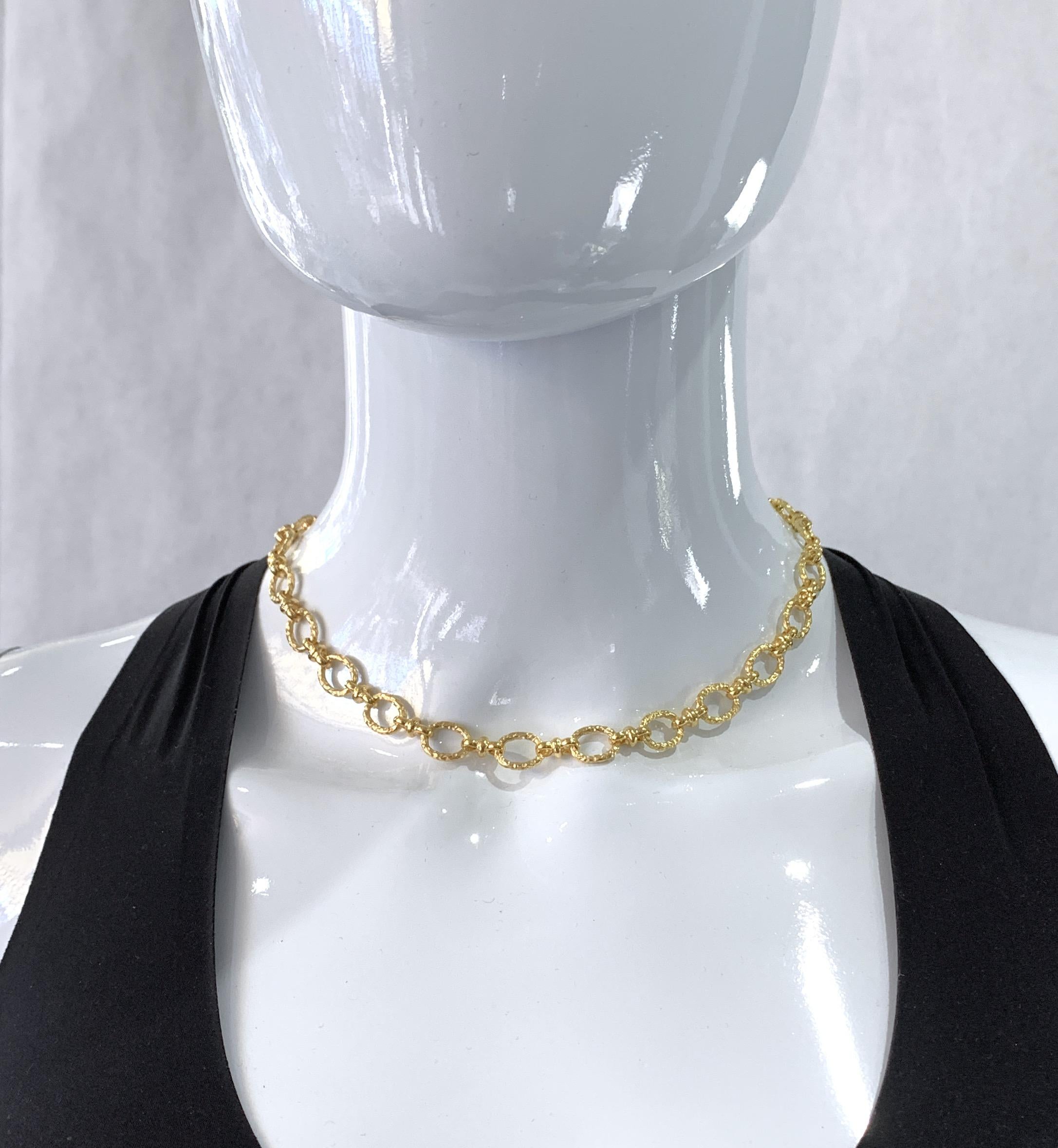 This striking and sexy handmade chain in rich 18 karat yellow gold features hammered gold oval links that lie flat against the skin, nicely separated, thanks to figure eight connectors.   The ovals are irregular and have a matte finish, so they