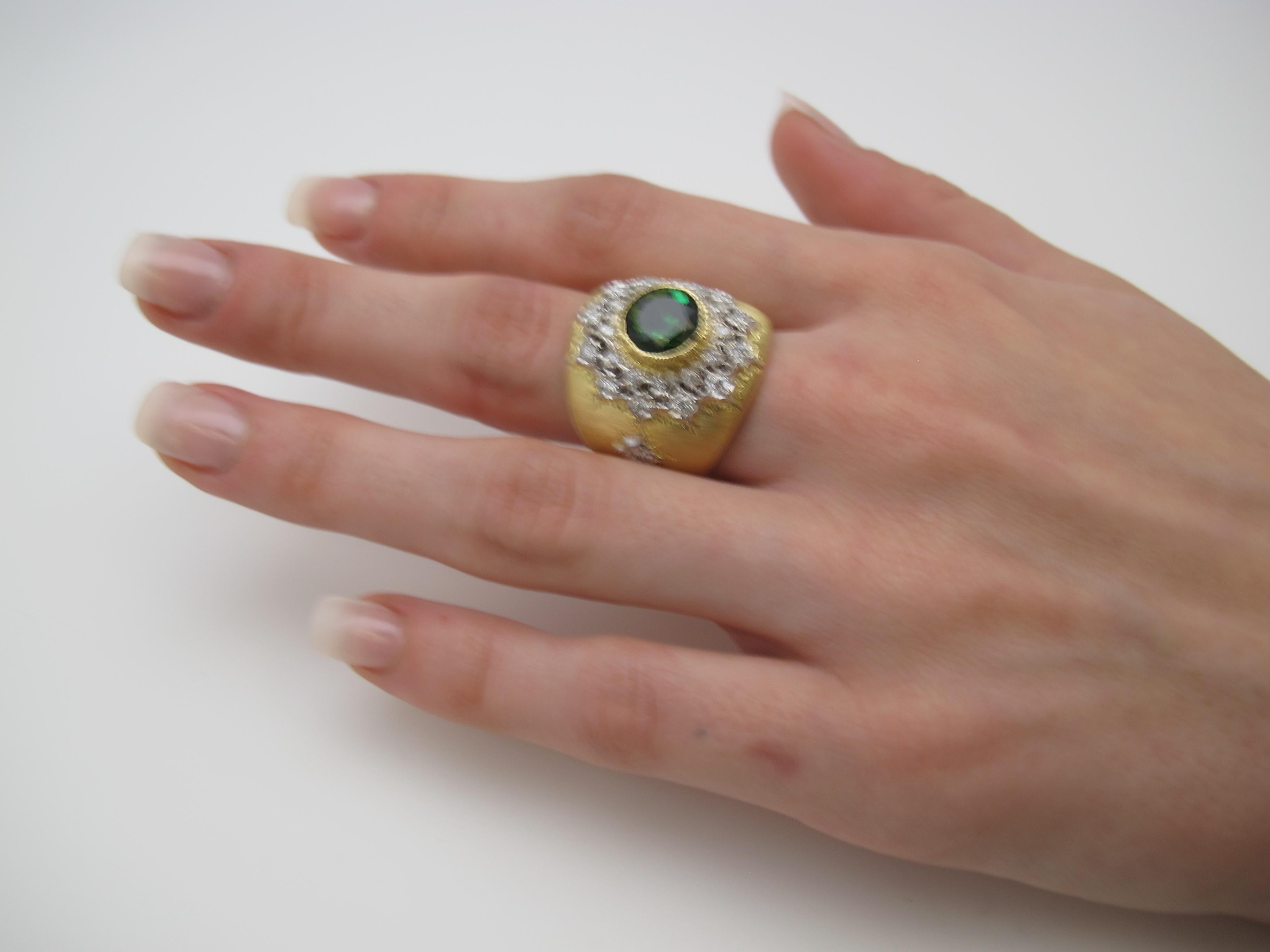 This luxurious Florentine style ring features a 2.75 carat, bright, bluish green tourmaline set in an elaborate 18k yellow gold bezel, surrounded by a nearly a carat of brilliant white diamonds. The diamonds have been individually set in a