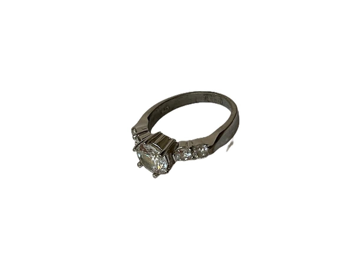 This is a sterling silver ring with faux diamonds.

The height of the center diamond is .25