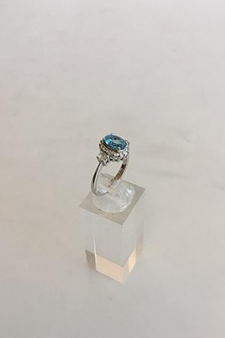 Ring in 14K White Gold with Blue Stone (Sapphire) Two Brilliants surrounded by 16 small stones. Ring size 54 / US 6 3/4. Weighs 3.48 g / 0.12 oz. Stamped 585