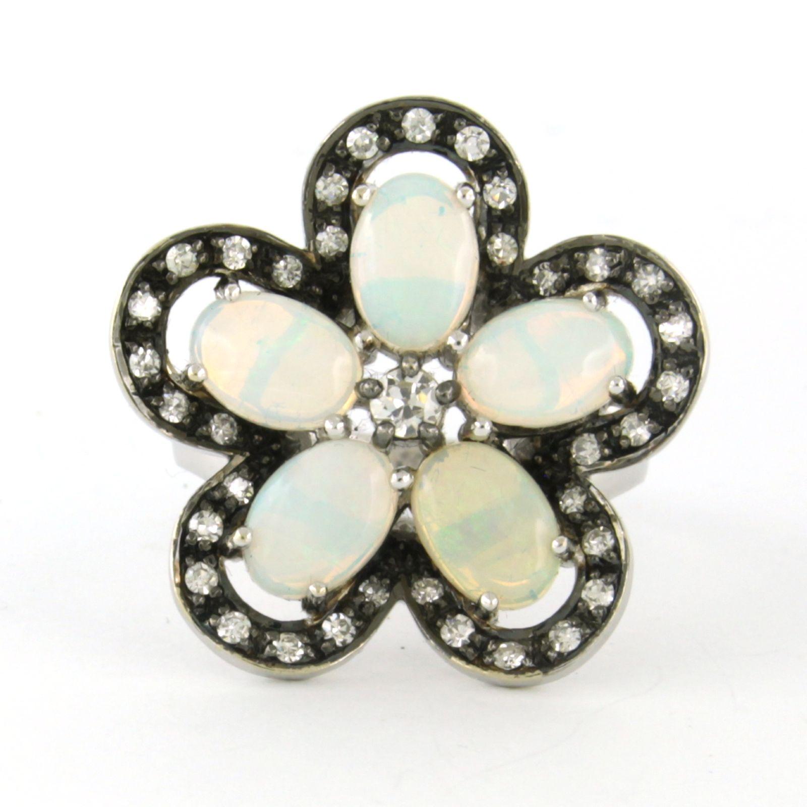 Ring aus 14 Karat Weißgold in Form einer Blume, besetzt mit Opal, bolschewistischen Diamanten und Diamanten im Einzelschliff - Ringgröße US 6.75 - EU 17.25 (54)

Ausführliche Beschreibung:

die Spitze des Rings ist schwarz rhodiniert und hat einen