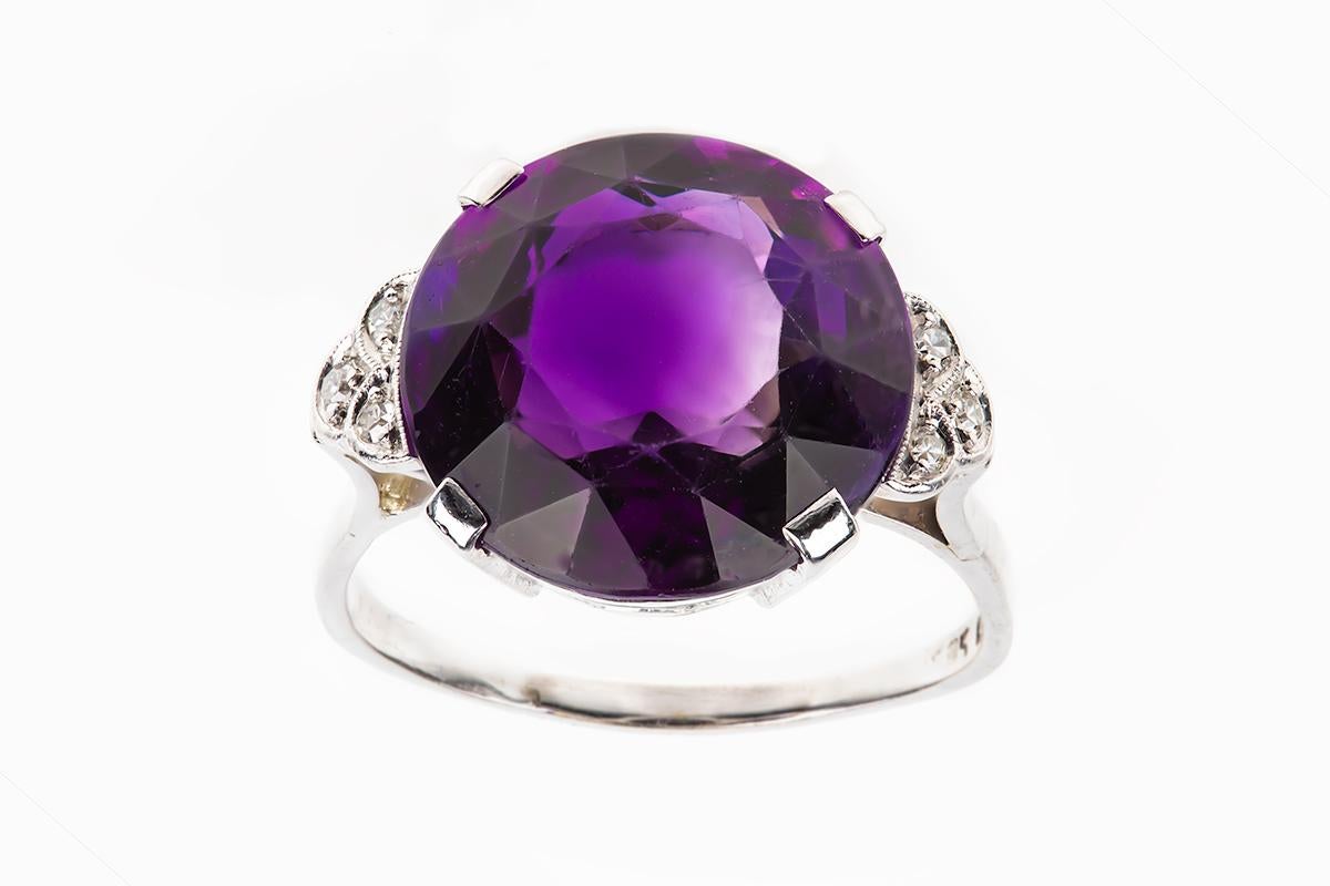 A stunning amethyst ring with diamond set shoulders in platinum. The amethyst is of a fine natural colour and Siberian in origin. It is circular cut in a claw setting with three brilliant cut diamonds either side.
Measures 18mm in width of stone x