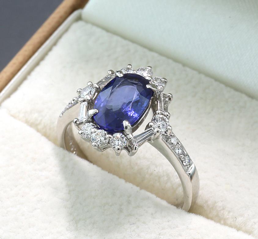 Ring with a sapphire approx. 1.67 carat, blue, transparent quality, oval shape. The sapphire is surrounded by a wreath of diamonds in tapered and brilliant cut, 8 diamonds are set in the shoulders. All 18 diamonds approx. 0,50 carat in total, color: