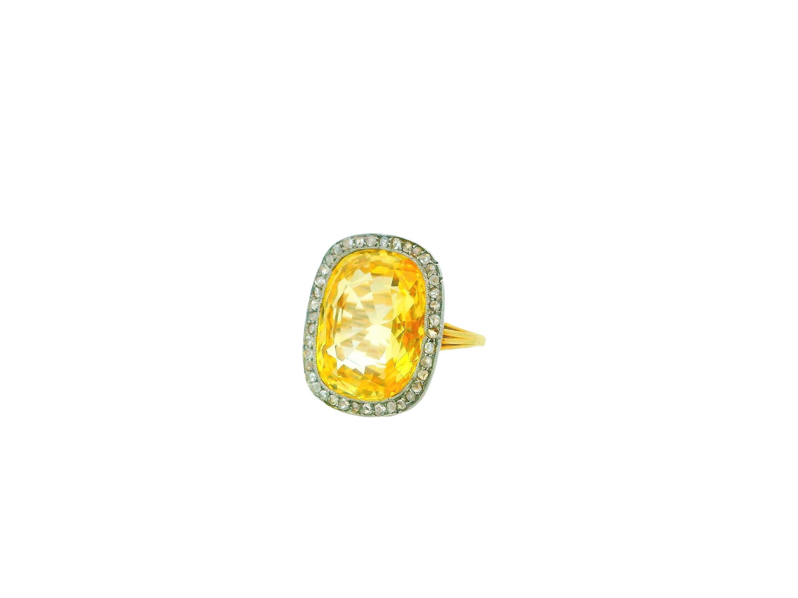 This exquisite ring is a study in brilliance, color, and elegance.

At its center is a magnificent approximately 20.0-carat yellow sapphire, cut in a stunning cushion shape that radiates a warm golden hue. The sapphire is surrounded by a halo of