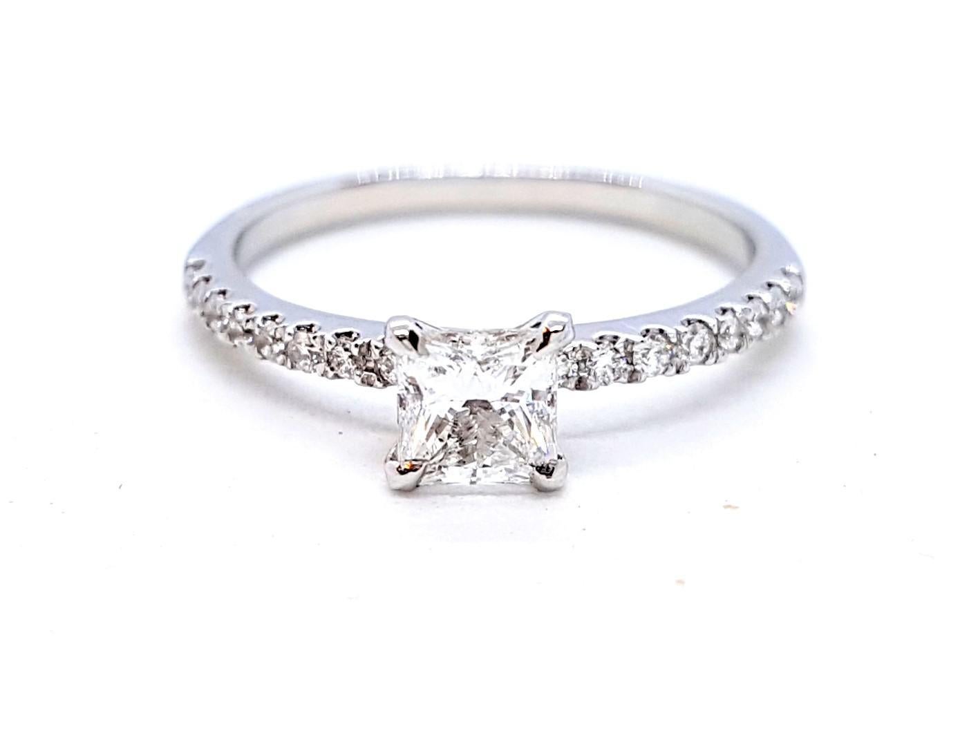 Solitary white gold 750 mils (18 carats). set with a central princess cut diamond E-SI1 0.50 ct HRD certified. and supported 16 round brilliant cut diamonds 0.16 ct total ring size: 53 width across the top 0.45 cm width of the ring: 0.14 cm. total