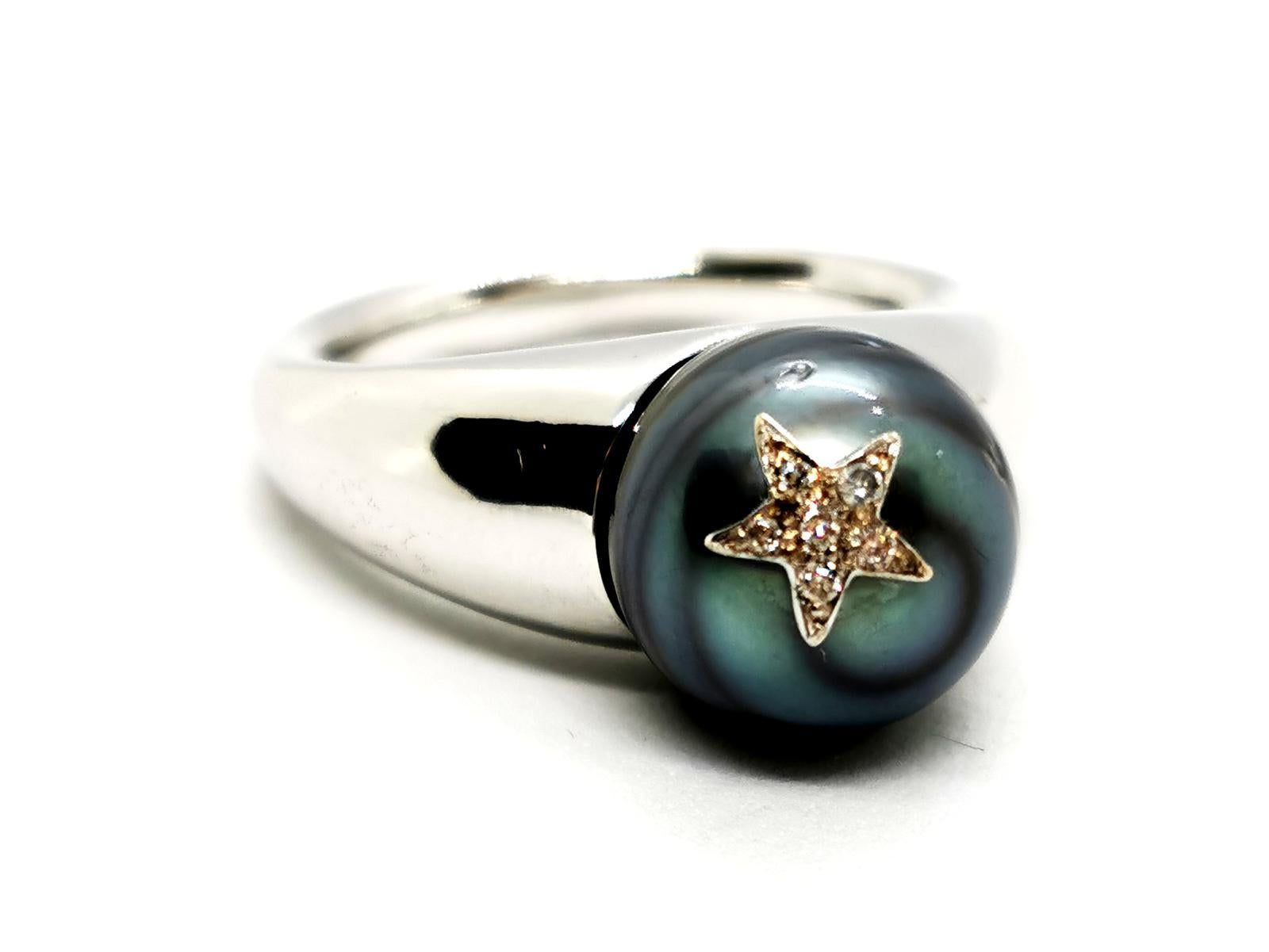 Ring in 750 thousandths (18 carats) white gold. set with a Tahitian pearl. diameter 10 mm. star motif in white. set with 6 diamonds. brilliant cut. for a total of approximately 0.03 ct. size: 51. top width: 1.02cm. total weight: 10.84g. eagle's head