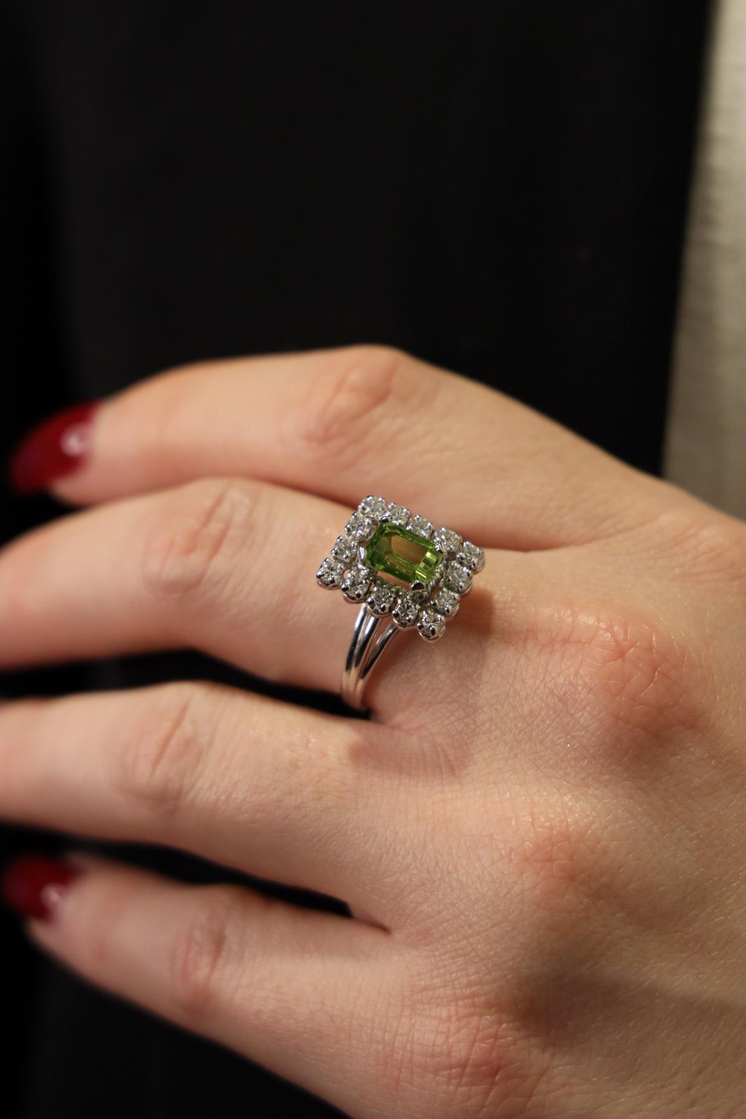Ring in white gold 750 thousandths (18 carats). set with an emerald-cut peridot of 1.16 ct. and a paving of 14 brilliant-cut diamonds. about 0.04 ct each. Total approximate weight of diamonds: 0.56 cts. Width on the top: 1.40 cm. Finger size: 55.