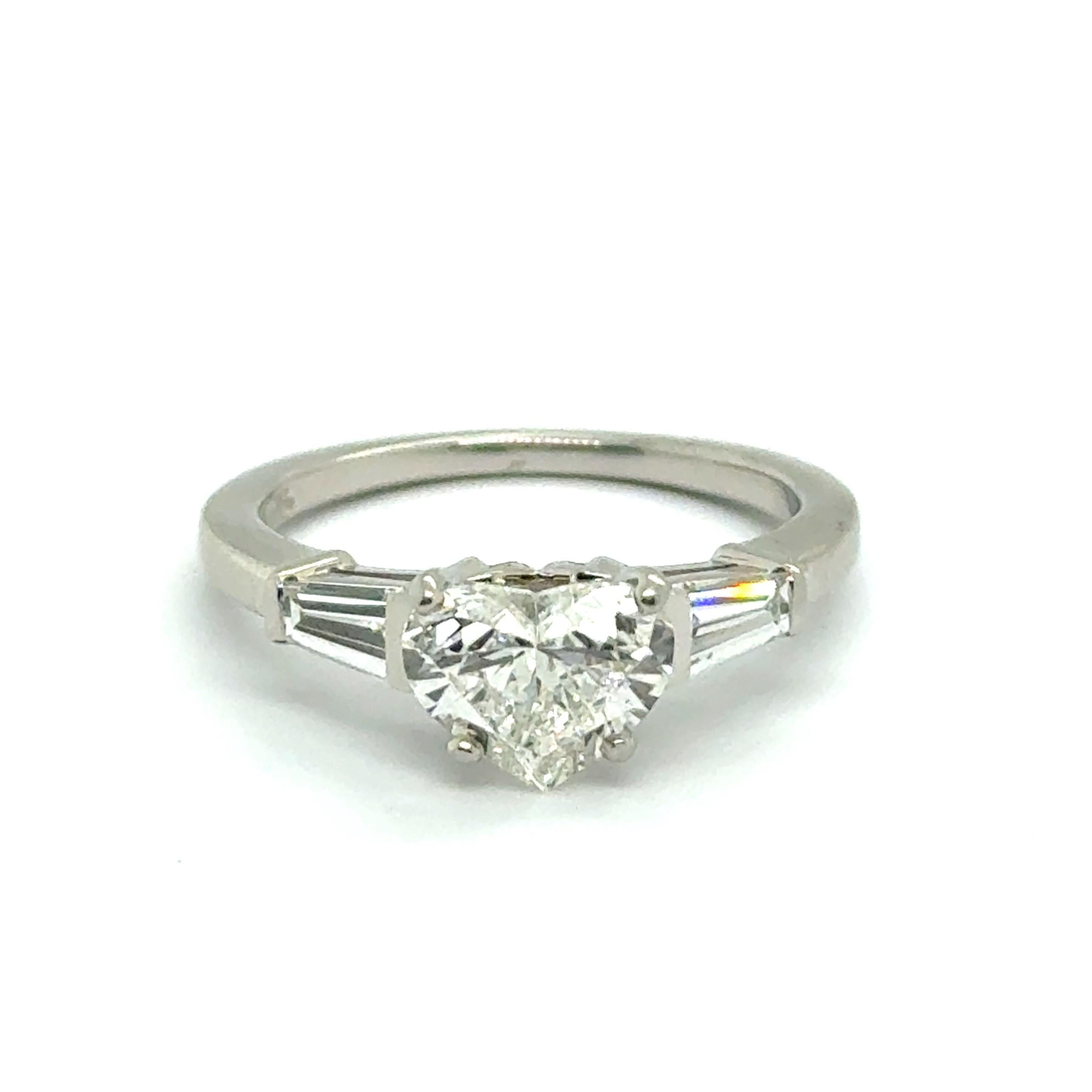 This enchanting Bvlgari ring, crafted entirely in platinum 950, is a true symbol of timeless love and elegance. 

Its centerpiece is an elegant heart-shaped diamond of 1.08 carats, boasting a dazzling H color and vs1 clarity. Flanking this radiant