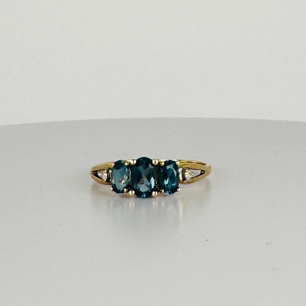 Cette magnifique bague vintage attire tous les regards ! Doté de trois magnifiques pierres en topaze bleue de Londres, il brille de teintes riches et profondes qui lui confèrent une allure chic et sans effort. De plus, elle est rehaussée de deux