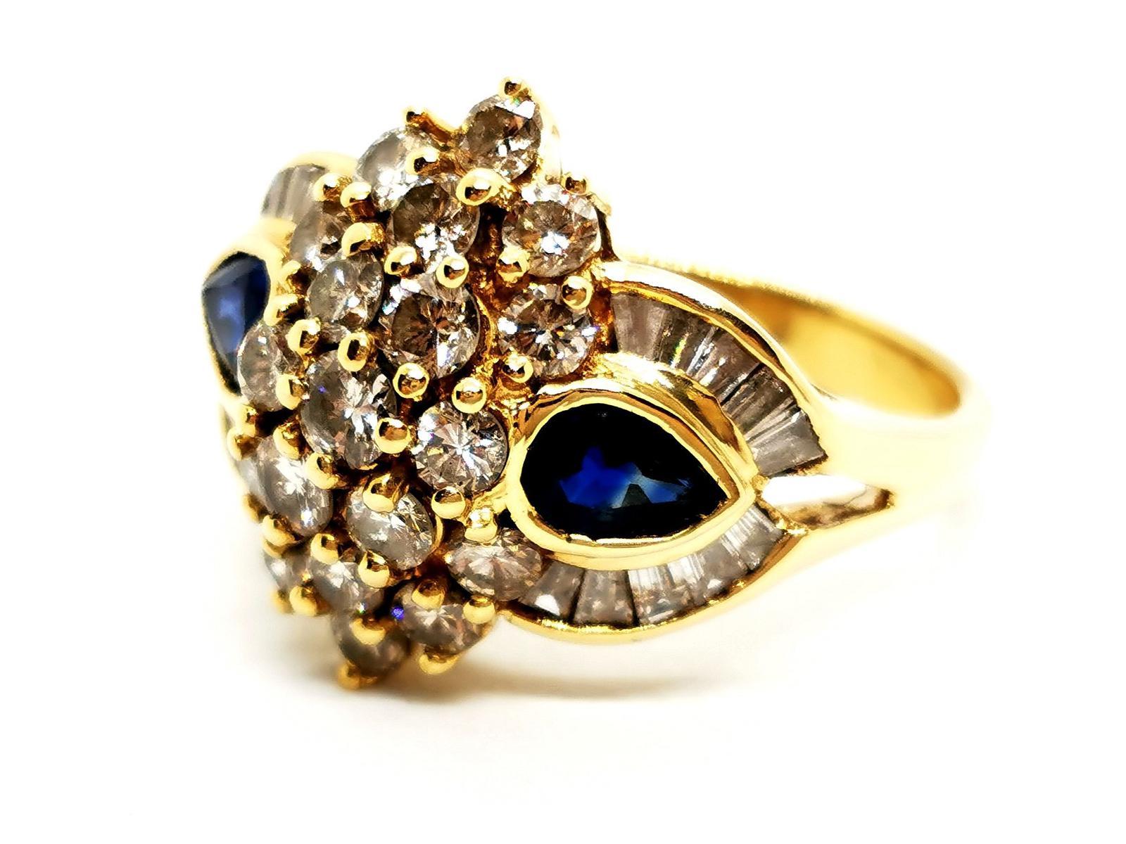 Yellow gold ring 750 mils (18 carats). diamond and blue sapphire. consisting of a center 19 of brilliant-cut diamonds. about 1.46 ct in total. supported by two blue sapphires cut pear. from about 0.355 ct each surrounded by lines 20 baguette