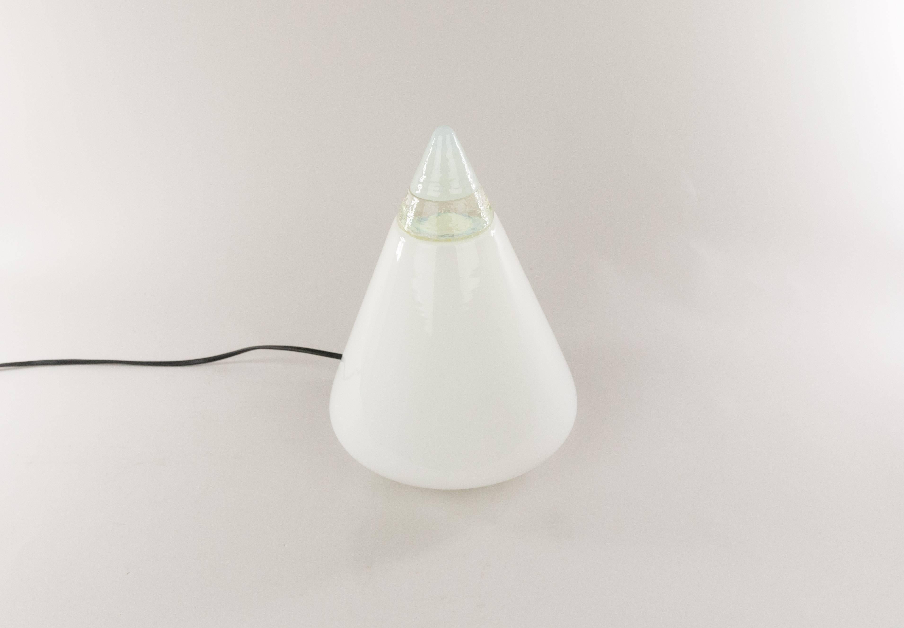 'Rio' table lamp designed by Giusto Toso for Italian manufacturer Leucos. 

The cone-shaped lamp is made of hand blown white glass and has a crystal band as a decoration. 

The glass part is supported by a metal base that is lacquered in white.