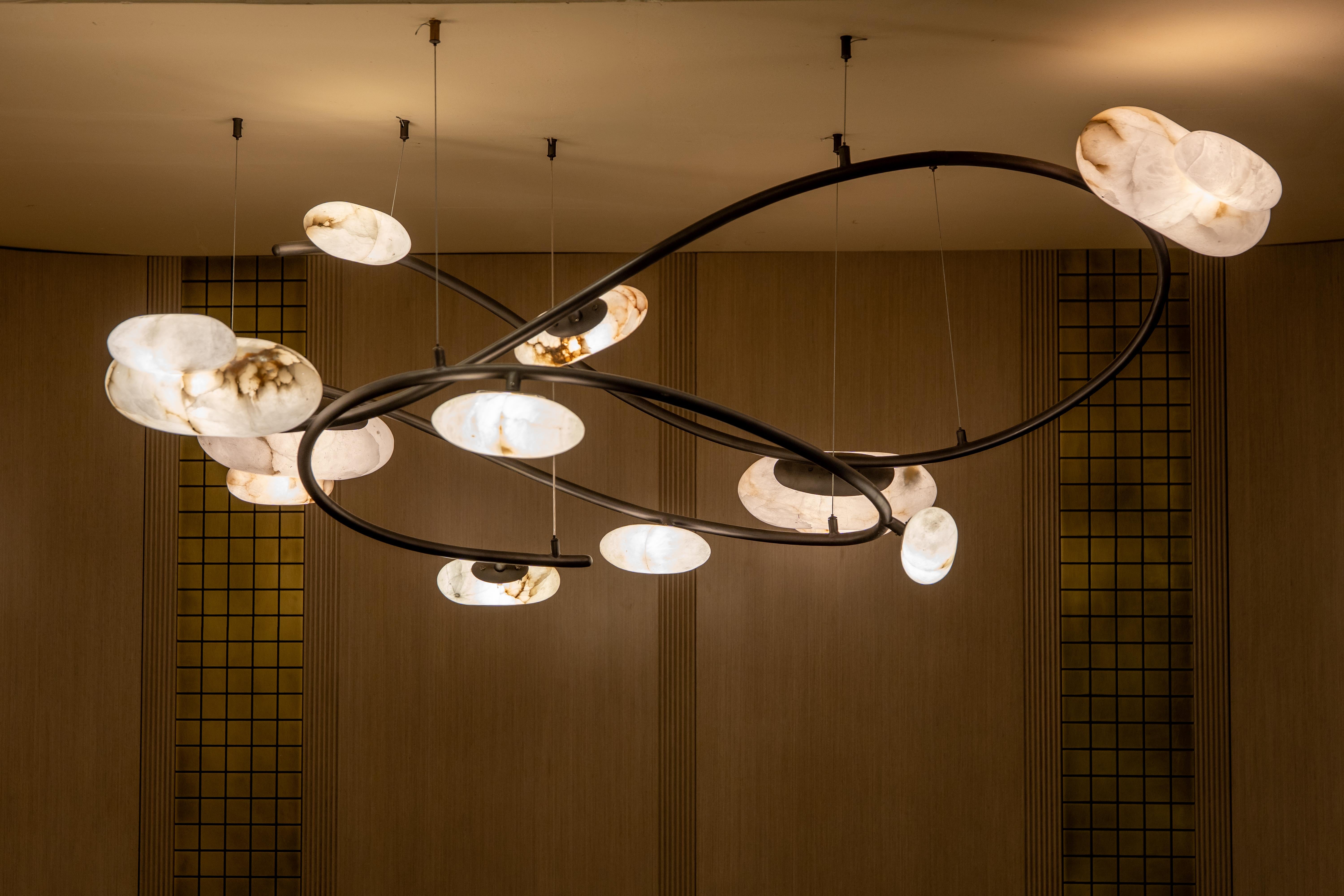 Introduce a captivating statement piece to your space with this exquisite modern chandelier. Inspired by the fluidity of nature, its design features elegant, sweeping curves that support a constellation of alabaster-like diffusers, each glowing with