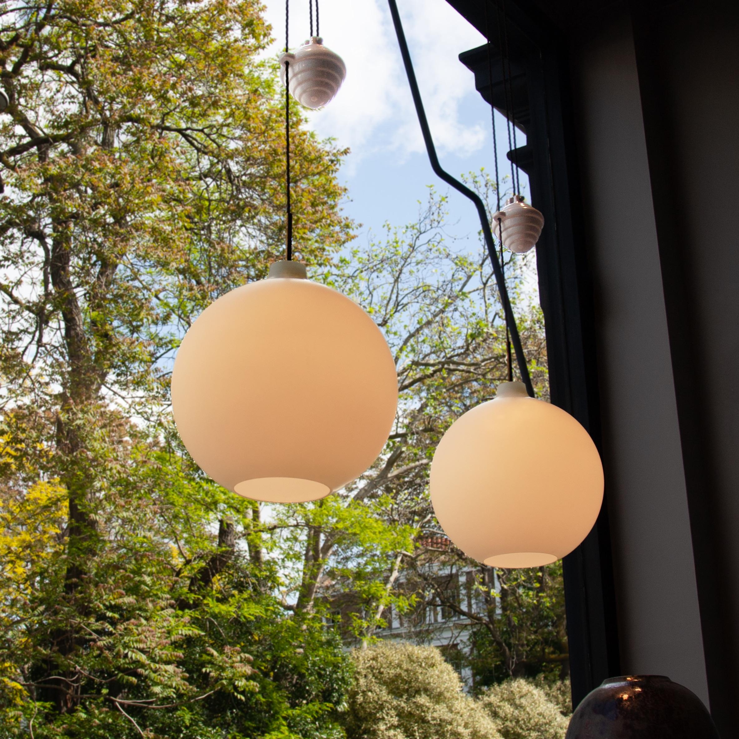 A vintage example of Wilhelm Wohlert's Satellit Pendel, with a ceramic rise & fall mechanism.

Designed in 1949 in collaboration with Louis Poulson, the lampshade is made from a thick, opaque, white glass, which softly diffuses light evenly