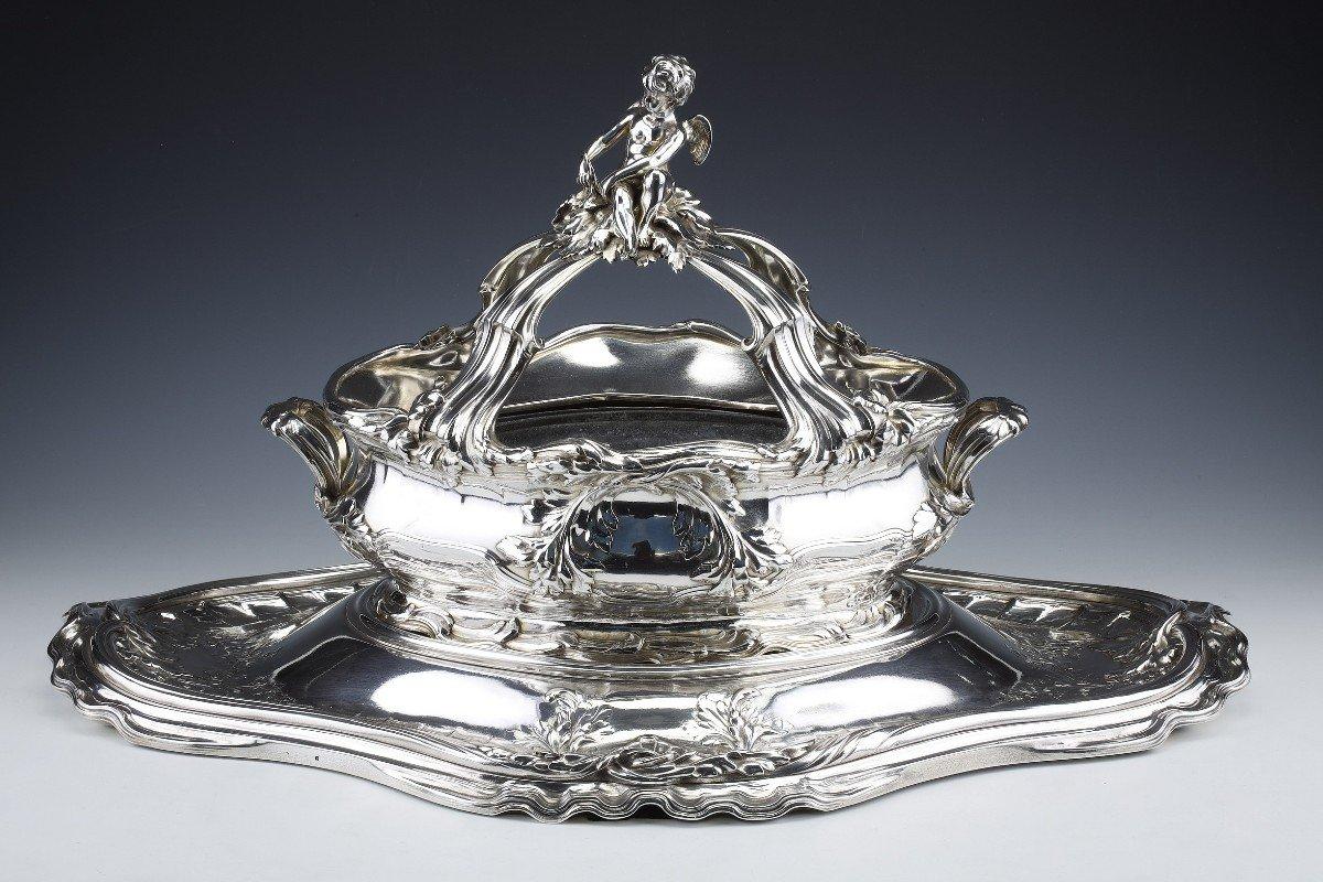 Importante centro de mesa de plata maciza en dos partes formado por una bandeja decorada con olas y una maceta coronada por un putti, decorada con conchas y crustáceos.
Dimensiones: bandeja 73 cm X 47 cm
                        Jardinera; 47cm X30cm