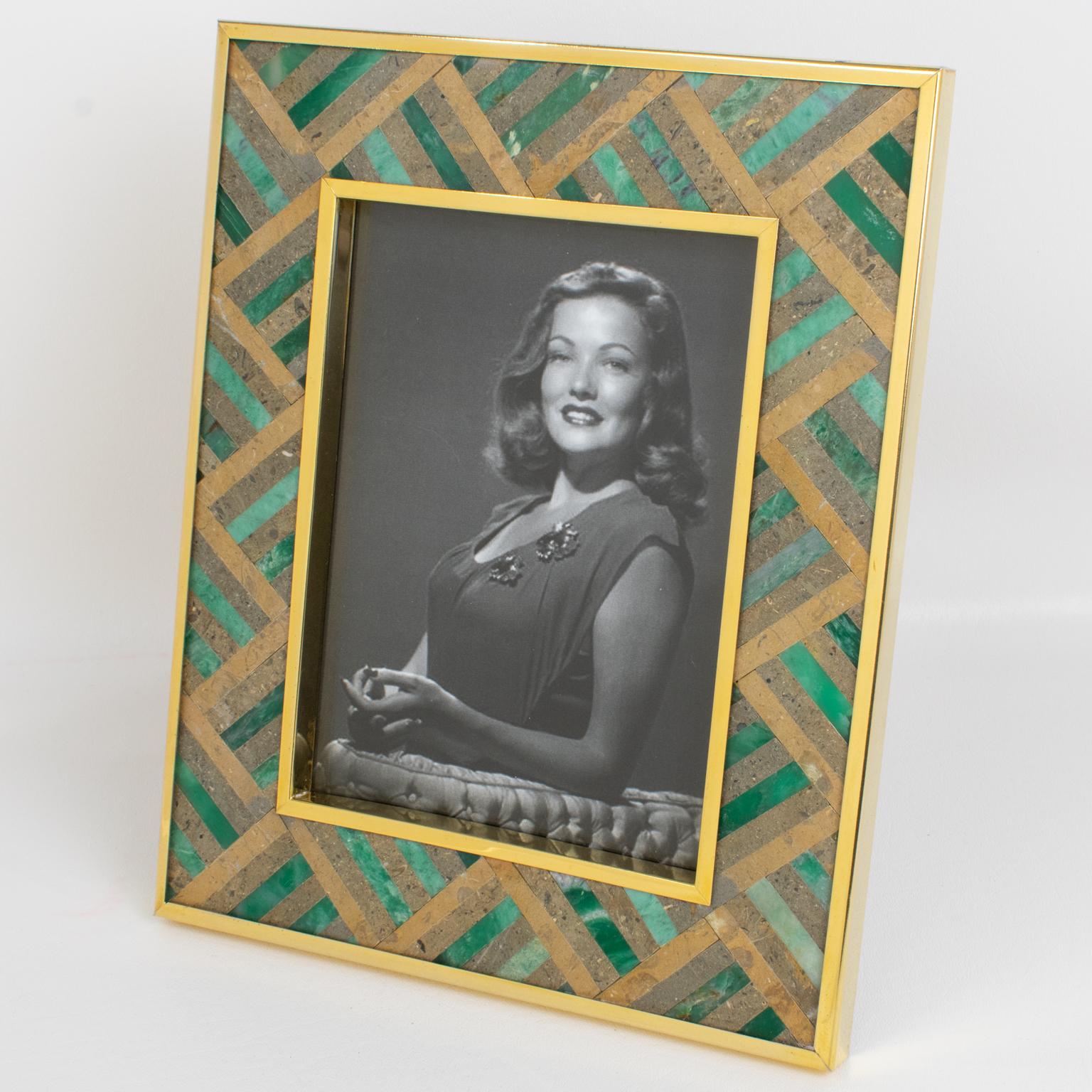 This elegant gilded brass and stone picture photo frame was designed by Italian designer Rita Frascione, Firenze, in the 1980s. The piece features a gilded metal framing with stone marquetry inlaid. The hard gemstones building the marquetry are