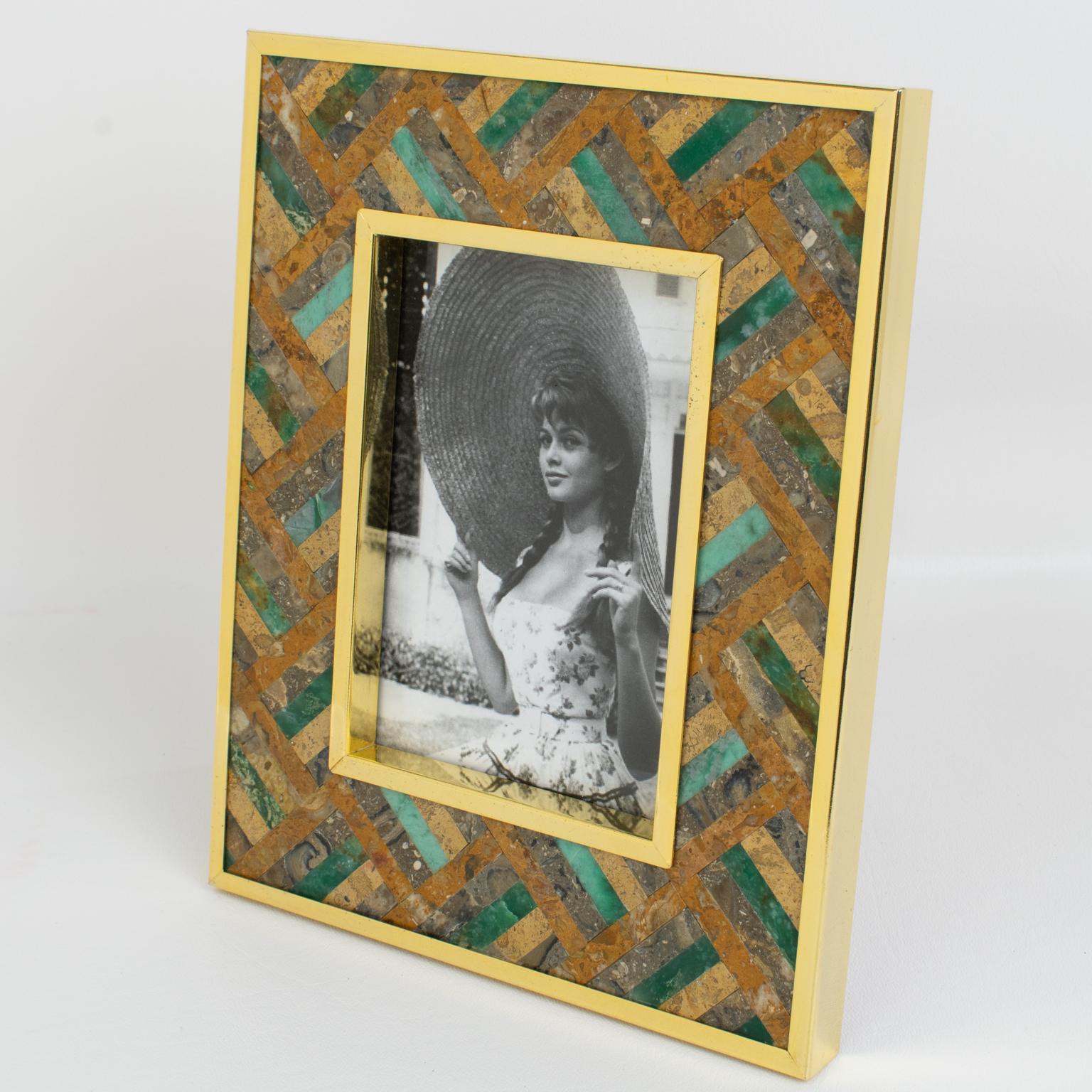 A lovely gilded brass and stone picture photo frame designed by Italian designer Rita Frascione, Firenze, in the 1980s. 
The photo frame features a gilded metal framing with stone marquetry inlaid. The hard gemstones used are crystalline rocks like