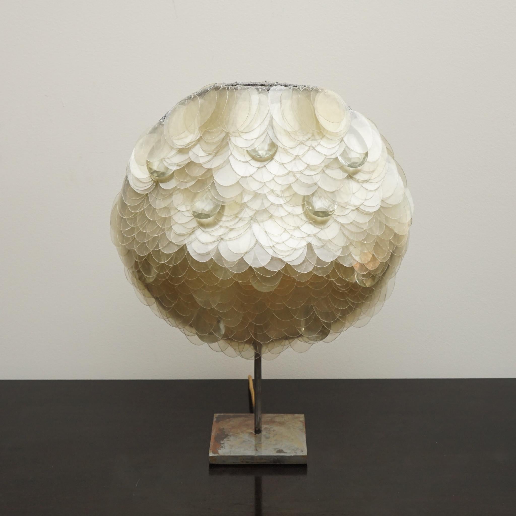 La lampe de table Ritagli, présentée ici, est la création de la designer italienne Valentina Giovando. Dotée d'un abat-jour composé d'écailles en fibre de verre, chacune individuellement découpée à la main et cousue à la base en fer, la lampe