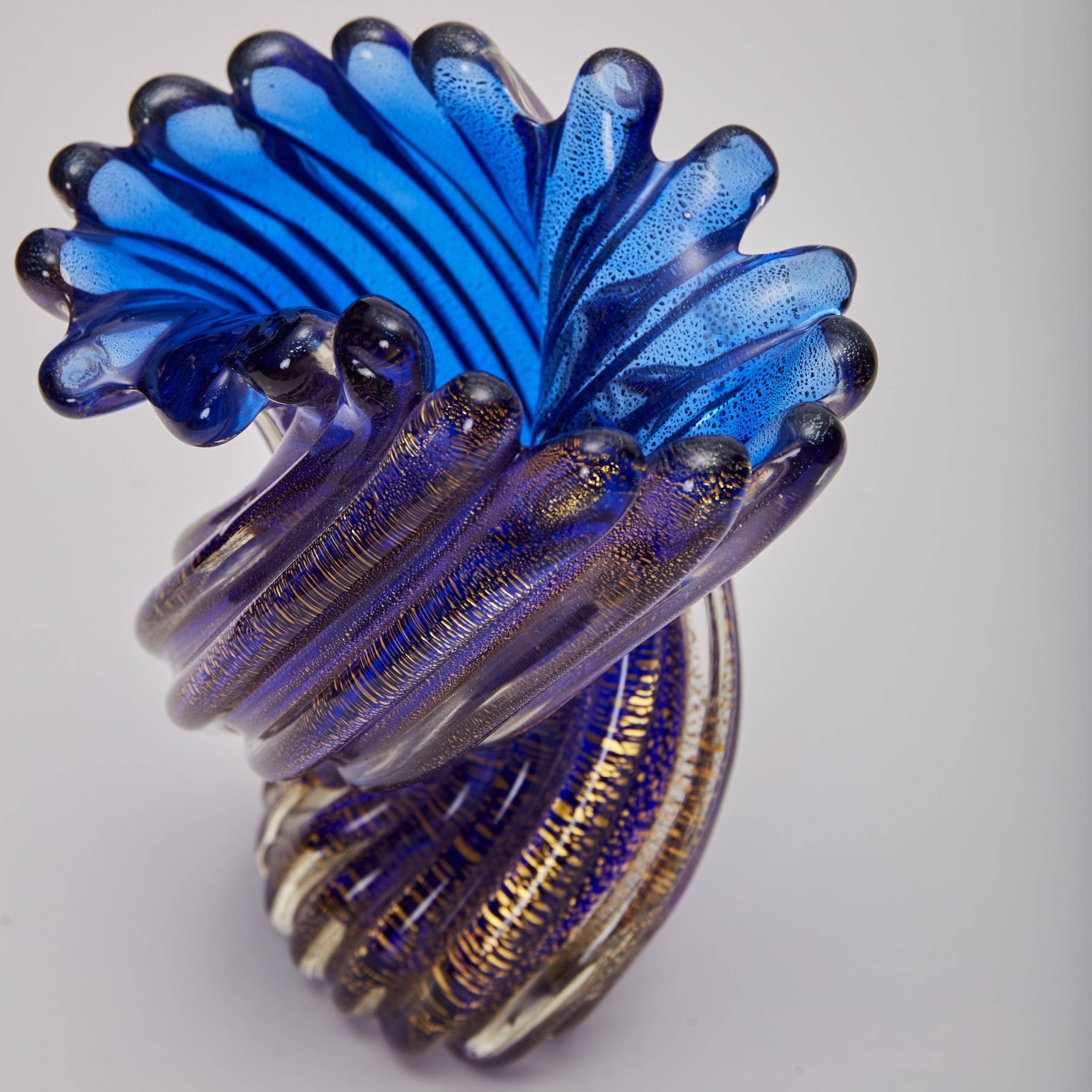 Ritorto means twined in Italian. This hand blown glass vase is made up of columns of translucent twisted glass to form a spiral shaped vase in Persian blue. The ribbed vessel is enhanced by a rainfall of gold leaf flecks throughout its body.
