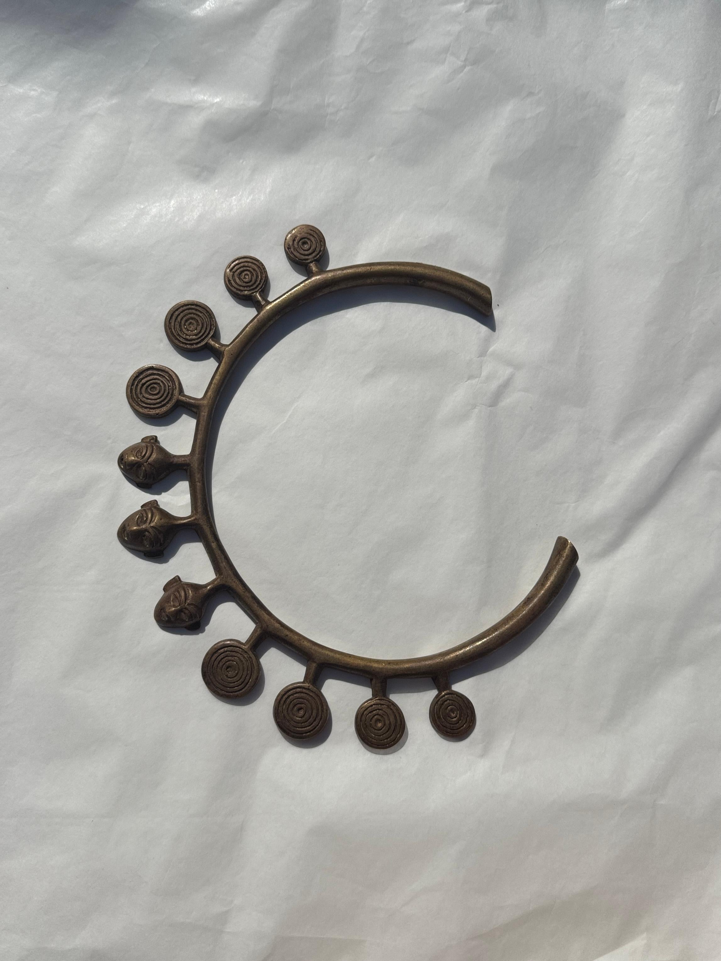 This striking bronze piece, crafted using the ancient lost-wax technique, originates from the captivating culture of the Konyak Naga, one of the last known headhunter tribes of Northeast India.

The bold, crescent-shaped collar is adorned with three