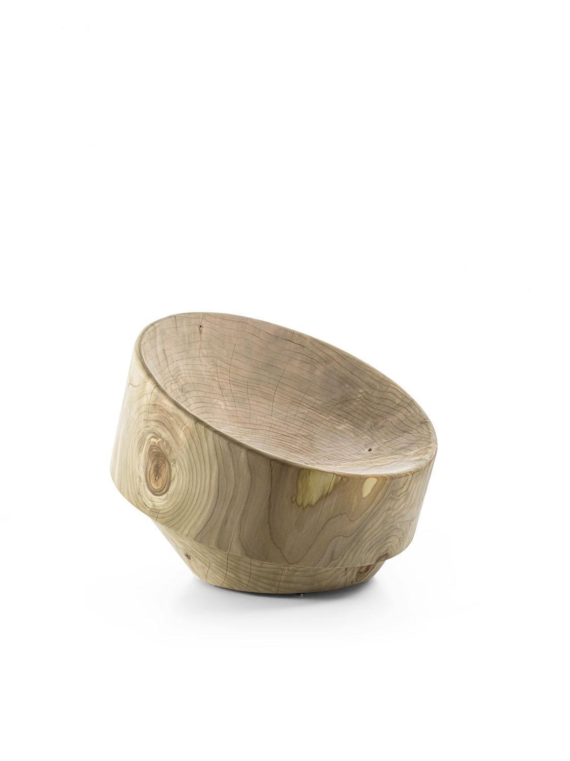 The Palio Armchair, designed by Ronald Sasson for Riva 1920, is a sculptural monolith carved from a single block of scented solid cedar wood. Its curvilinear design flows seamlessly from the ergonomic seat into the backrest, embodying both comfort