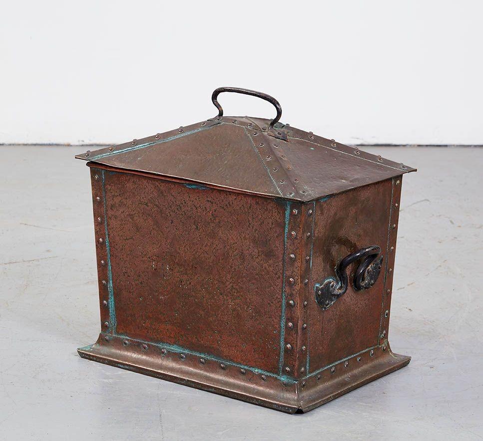 A riveted copper Arts and Crafts kindling box with four canted sides on a footed base with hand-forged decorative iron handles, topped by a hipped lid with reinforced riveted seams and an iron handle. Patinated finish, and zinc interior liner still