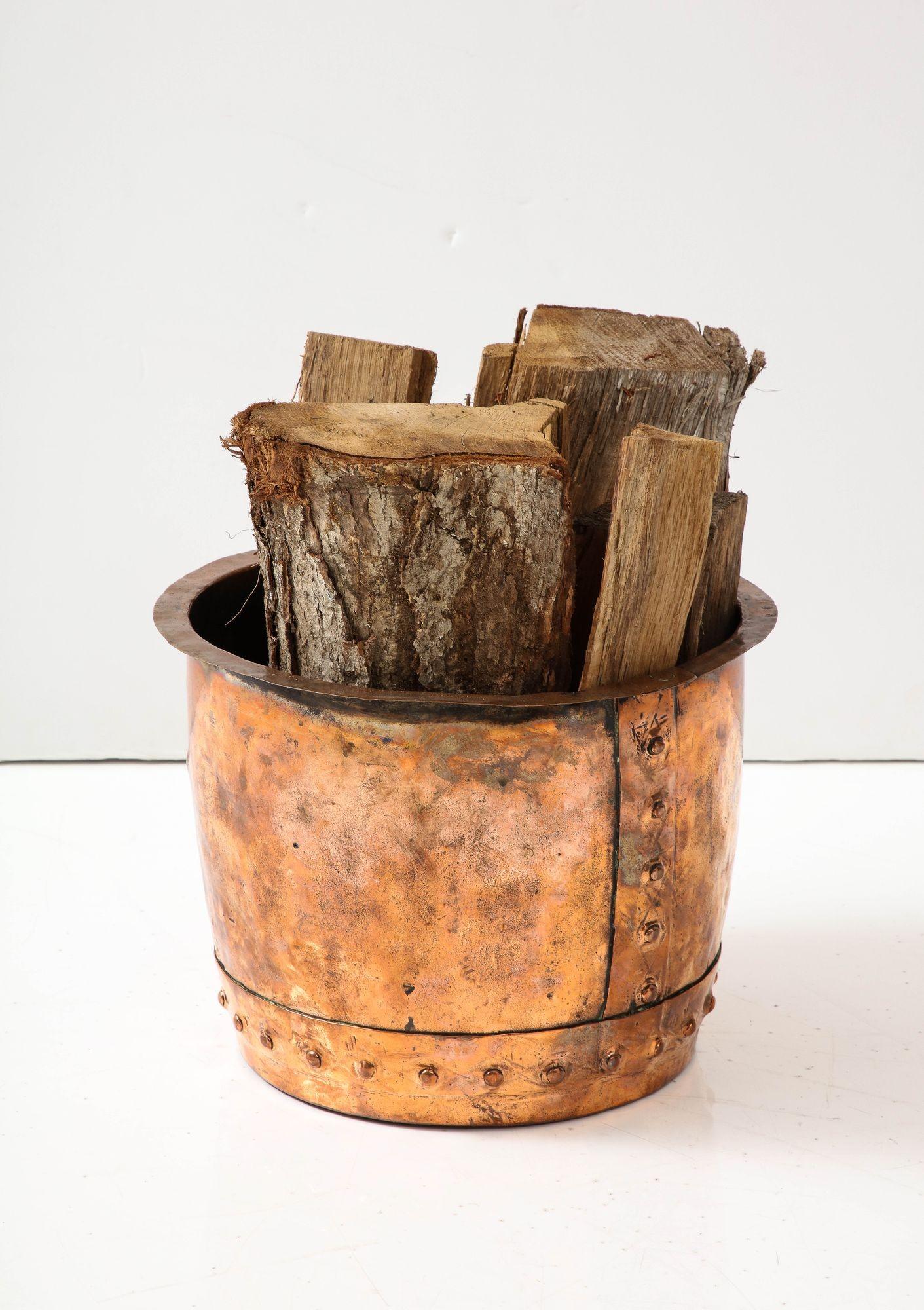 A copper log bin in an attractive mottled copper finish with flat rim and gently curved sides with riveted vertical central seam and riveted horizontal base seam.  Useful for logs or kindling next to a fireplace.
 
AD