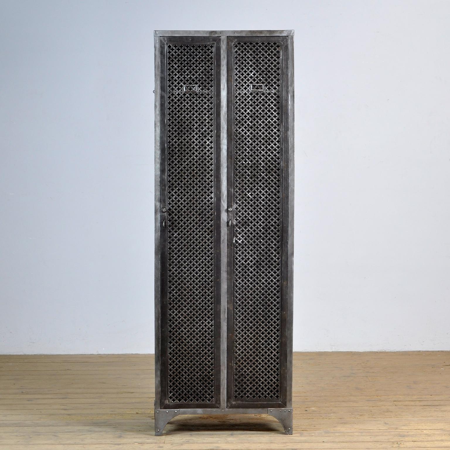 A German riveted iron locker from the 1930s. The locker has perforated doors with original locks and three clothes hooks and a shelf.