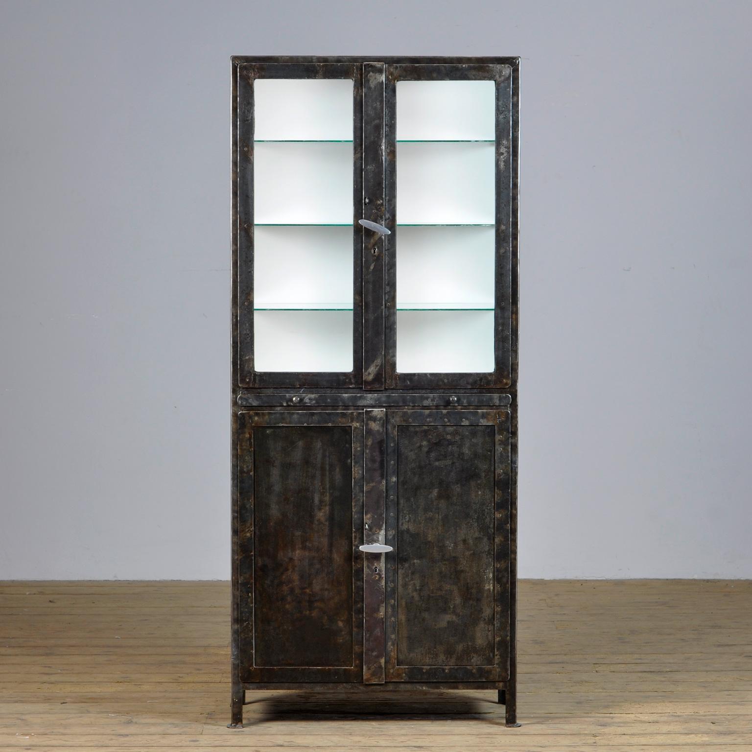 Riveted medicine cabinet from the 1920s. The case has been stripped of the paint on the outside and polished. The cabinet has an extendable worktop where instruments could be placed. Behind the 2 lower doors 2 drawers and two shelves. The cabinet