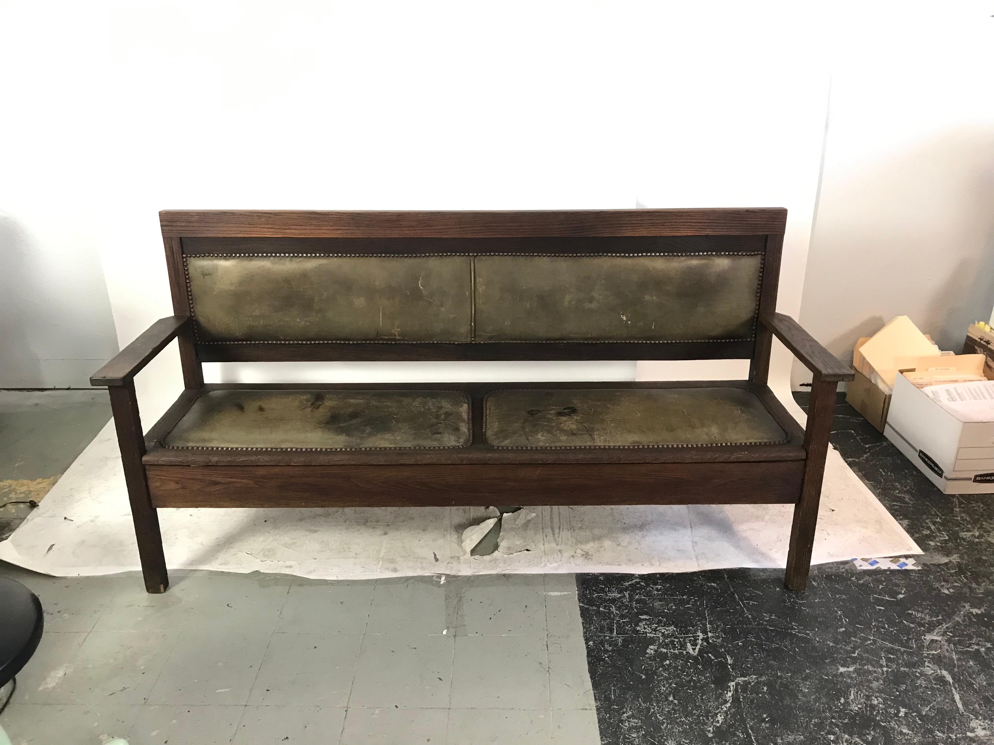 This is a wonderful riveted leather and oak bench from an Arkansas railroad depot, circa 1940. The backrest has leather upholstery on both the front and the backside trimmed with attractive brass tacks.