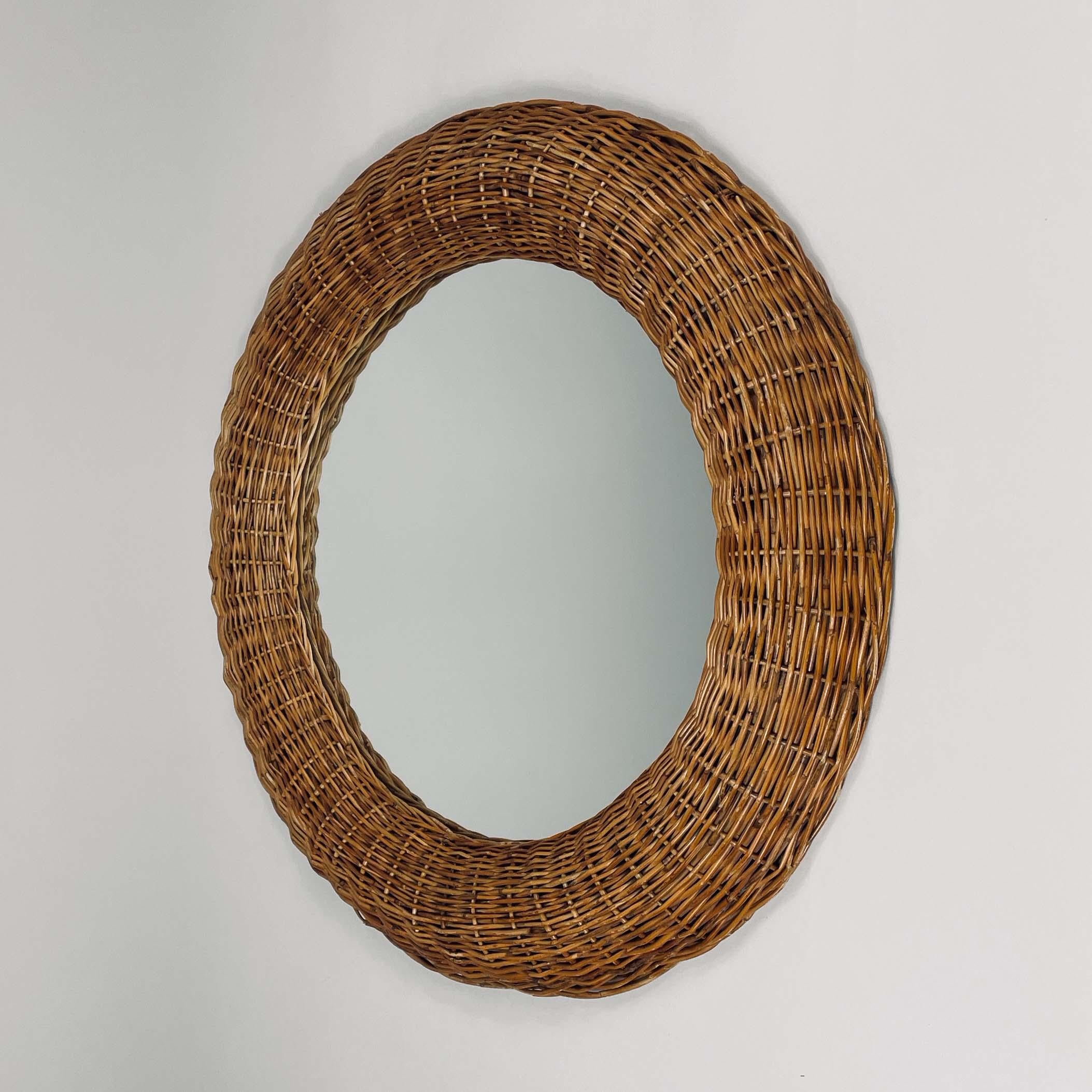 This vintage wall mirror was designed and manufactured in France in the 1950s. It features a hand woven rattan round frame with mirror glass.

Condition is good with few signs of age. Rattan with some minor wear. The mirror glass is original and