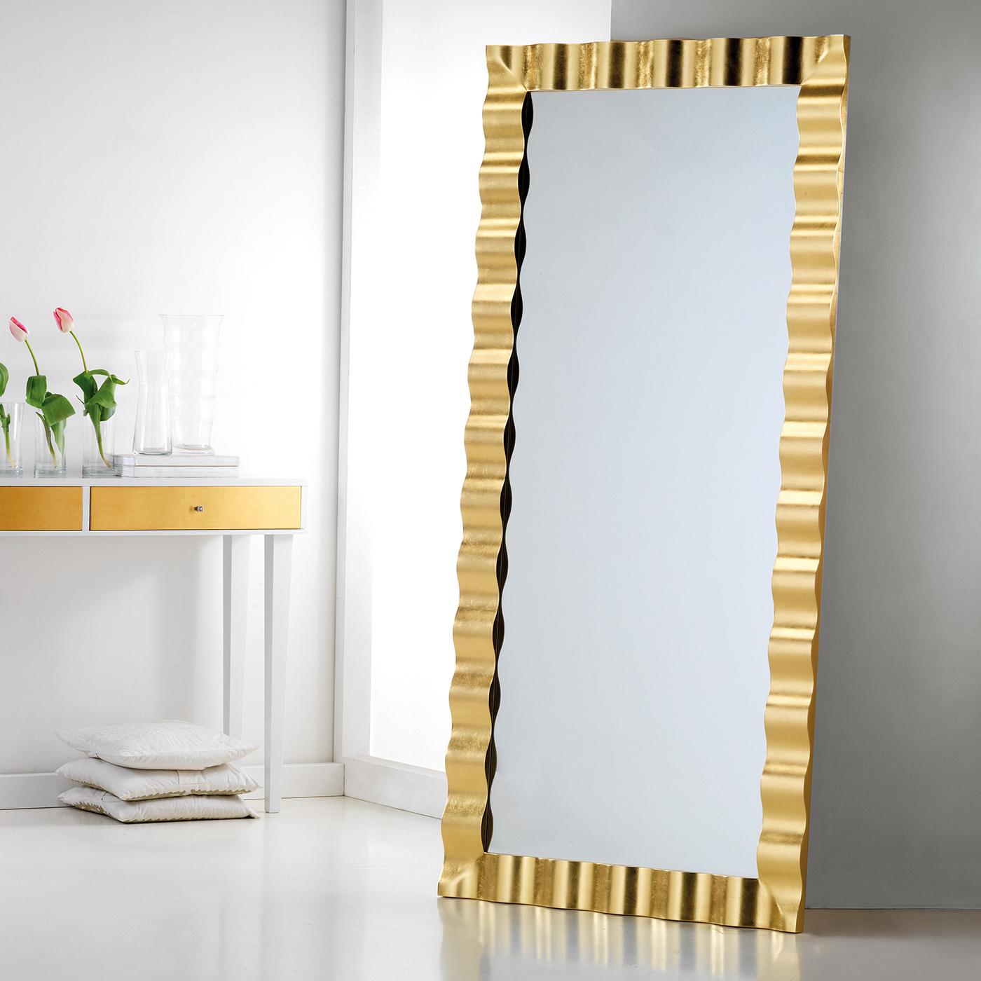 This mesmerizing wall mirror boasts a splendid wavy frame in fir wood. The 4mm-thick mirror is in prized Italian crystal, enclosed in the stunning frame (10 cm wide and 3.5 cm thick) finished by hand with gold leaf. The hooks fitted to the mirror's