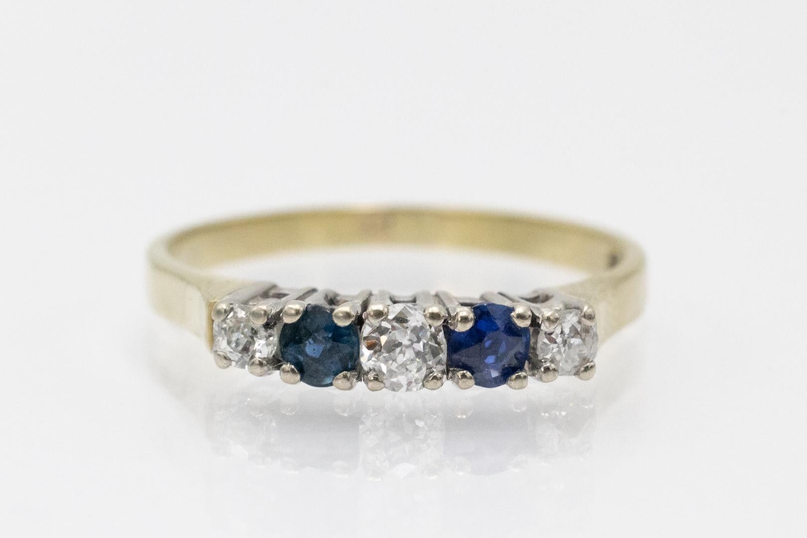 Anillo Rivière con zafiros naturales y diamantes talla antigua. Fabricada en oro amarillo y blanco de 14 quilates (ley 0,585). Este anillo clásico presenta tres diamantes talla antigua, con un total de 0,25 ct (claridad SI2, color J), y dos zafiros