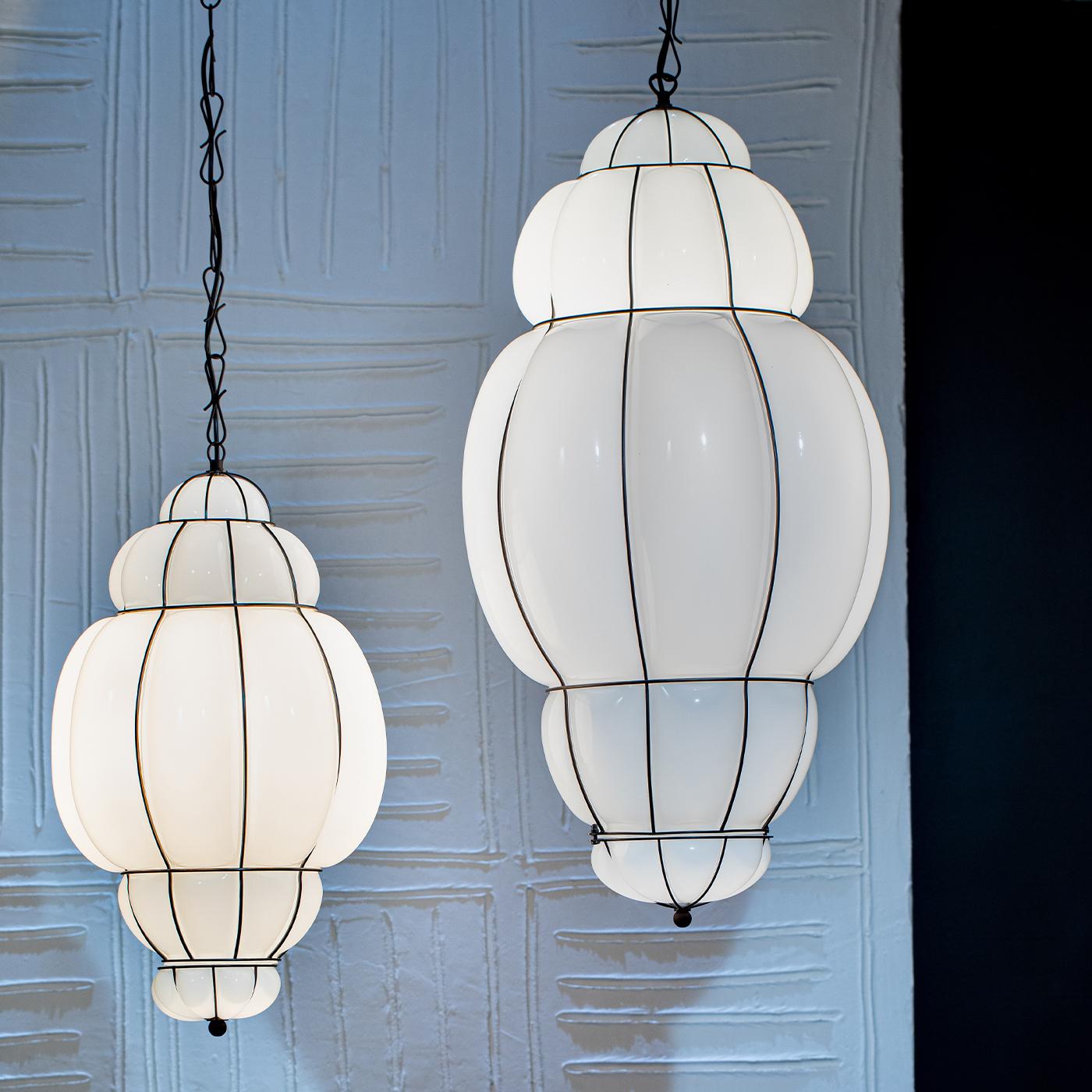 A showcase of glassblowing artistry rendered in a sophisticated modern evolution, this pendant lamp makes for a classy addition to modern entryways or bedrooms. The white Murano glass shade gets blown into a sleek stainless steel cage, from whose