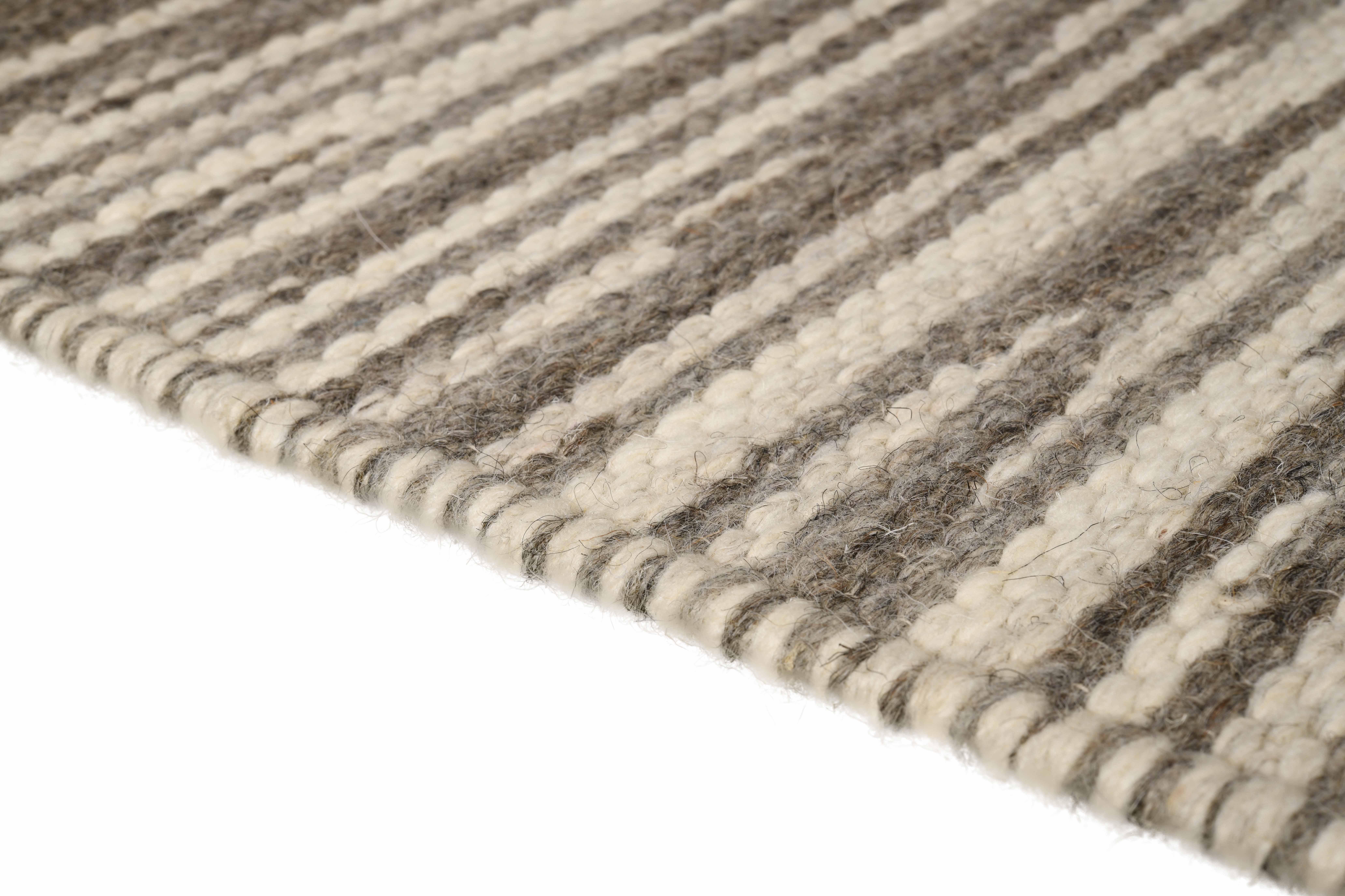 Rivus takes us on a journey like a graceful stream flowing aimlessly through the valleys. Undulating natural wool yarns meander thoughtfully through the high and low neutral tones, coalescing towards a subtle yet striking linear design.
